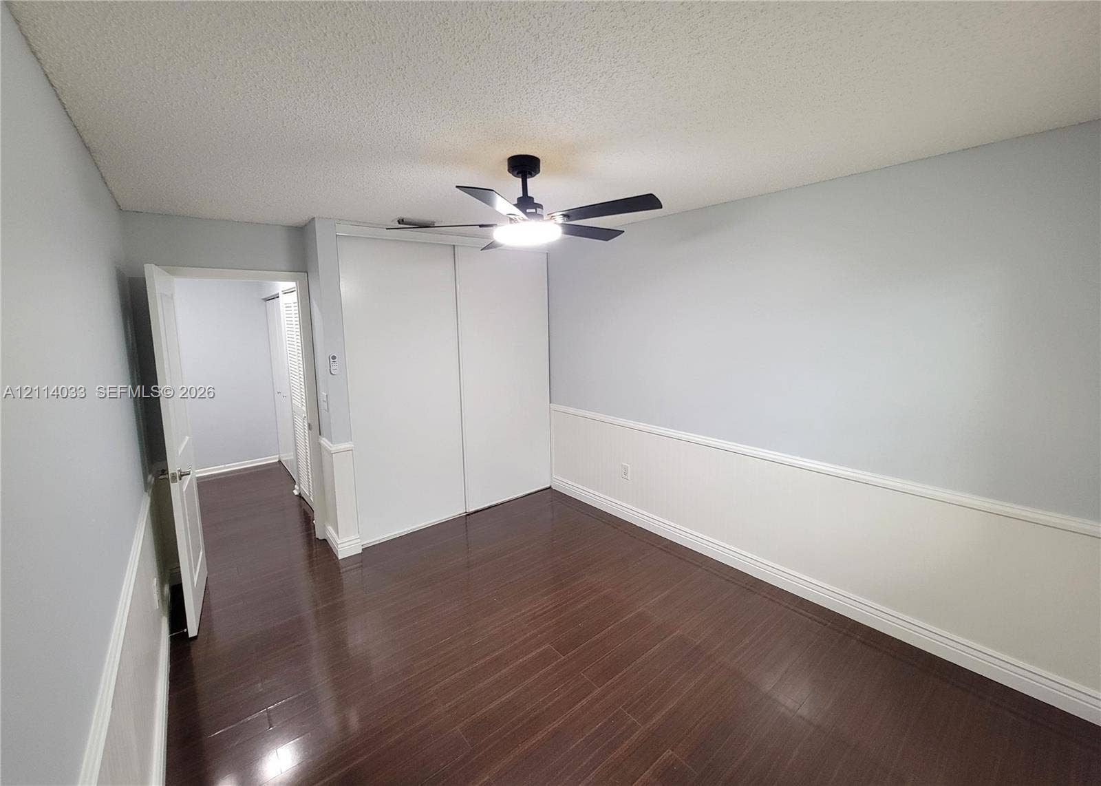 683 NW 88th Drive, Coral Springs, Coral Springs, FL 33071 Interior room featuring dark wood-finish flooring, two-tone walls with chair rail molding, a sliding-door closet, and an attached ceiling fan with integrated lighting