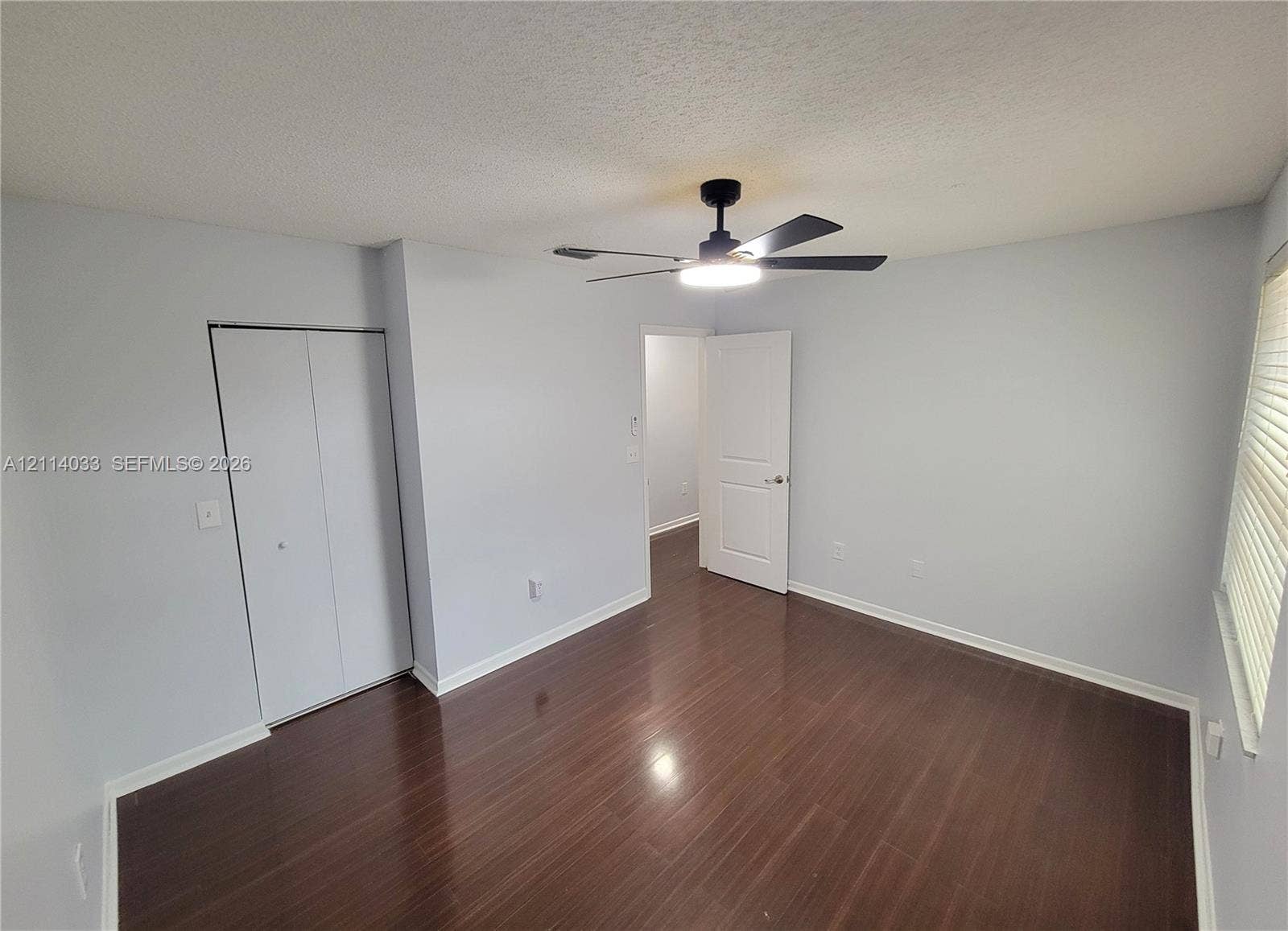 683 NW 88th Drive, Coral Springs, Coral Springs, FL 33071 Room featuring dark wood-finish flooring, a matte black ceiling fan with an integrated light fixture, a bi-fold closet, and a white interior door