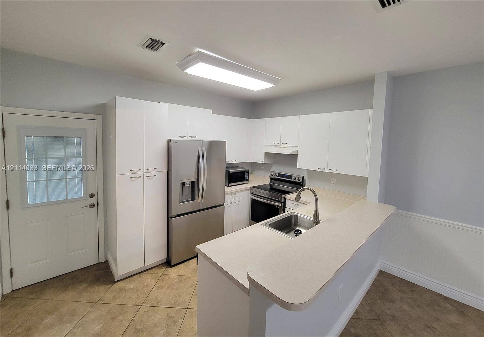 683 NW 88th Drive, Coral Springs, Coral Springs, FL 33071 Kitchen featuring white cabinetry, stainless steel appliances, a peninsula with a stainless steel sink, and tile flooring