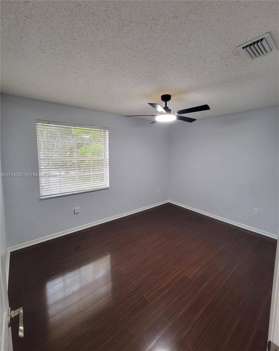 683 NW 88th Drive, Coral Springs, Coral Springs, FL 33071 Room featuring dark wood-finish flooring, neutral wall paint, and a ceiling-mounted light fixture with an integrated fan