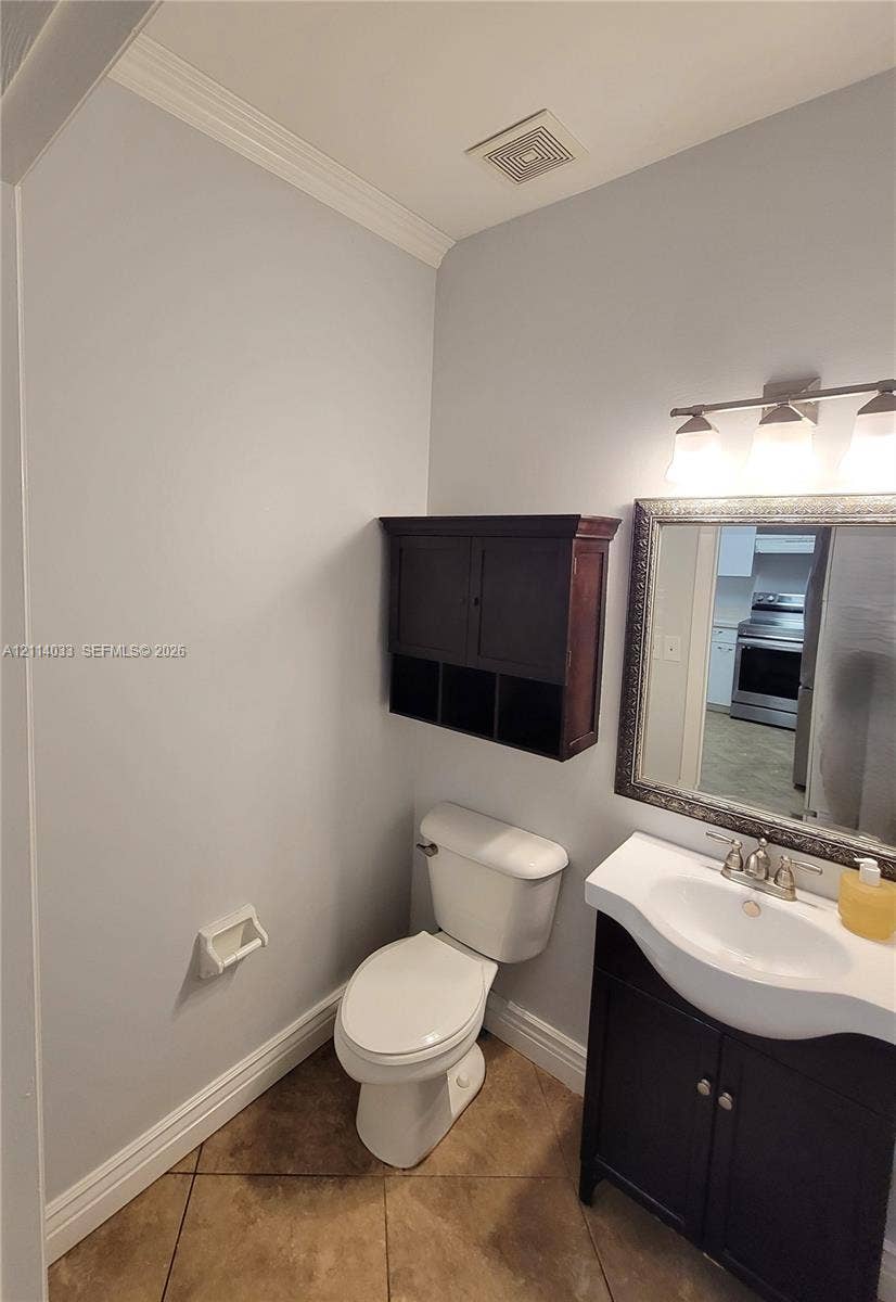 683 NW 88th Drive, Coral Springs, Coral Springs, FL 33071 Vanity with a molded sink, dark wood-finish cabinet, wall-mounted storage unit, three-bulb vanity light fixture, and tile flooring