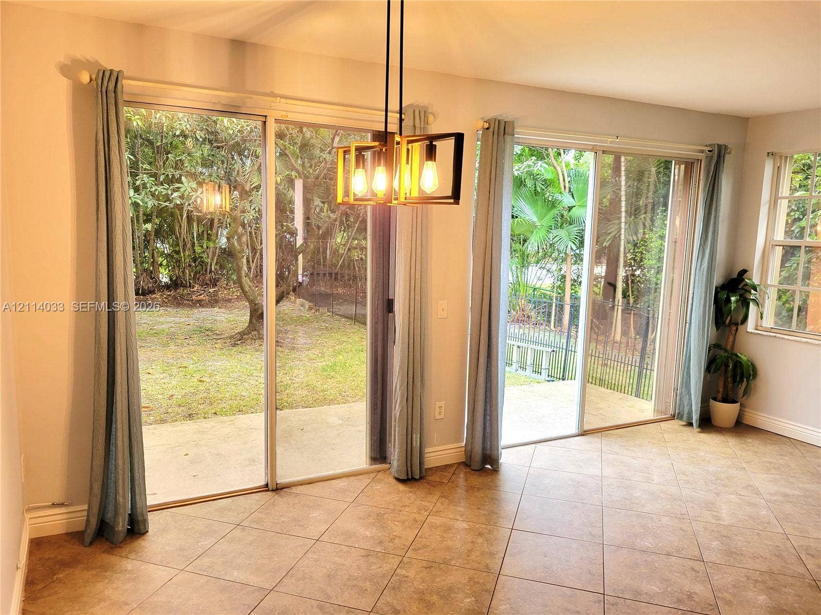 683 NW 88th Drive, Coral Springs, Coral Springs, FL 33071 Dual glass sliding doors, ceramic tile flooring, geometric metal pendant lighting, and access to a concrete patio