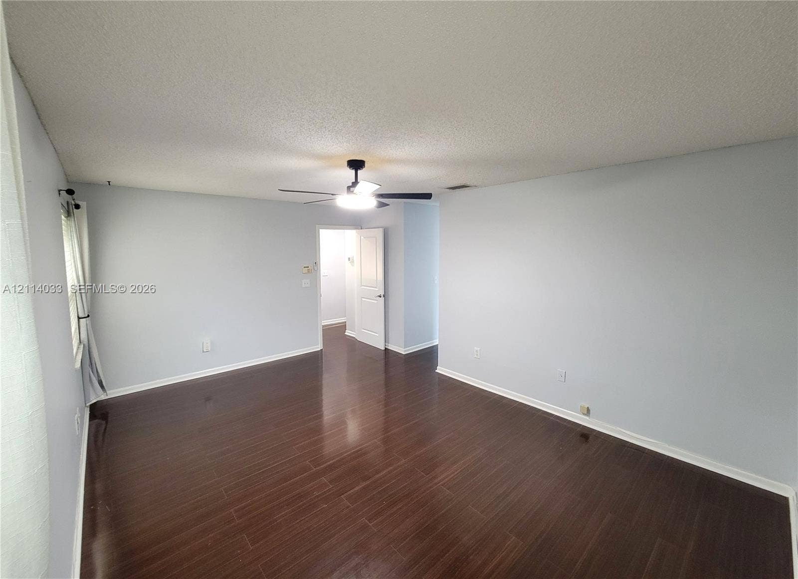 683 NW 88th Drive, Coral Springs, Coral Springs, FL 33071 Room featuring dark-toned wood-finish flooring, a central ceiling fan with integrated lighting, and a multi-panel interior door