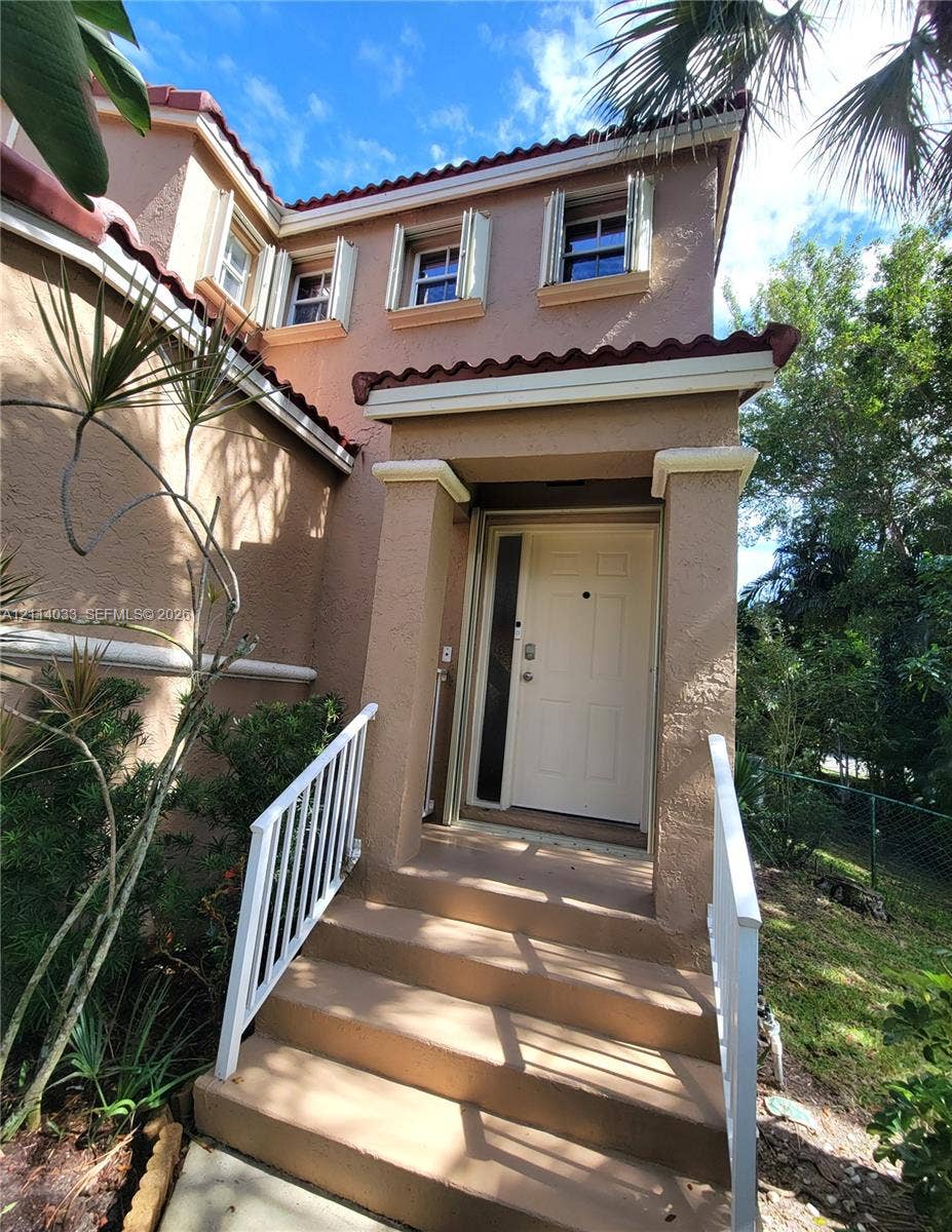 683 NW 88th Drive, Coral Springs, Coral Springs, FL 33071 Stucco exterior featuring a tiled roofline, covered entryway, and white metal railings