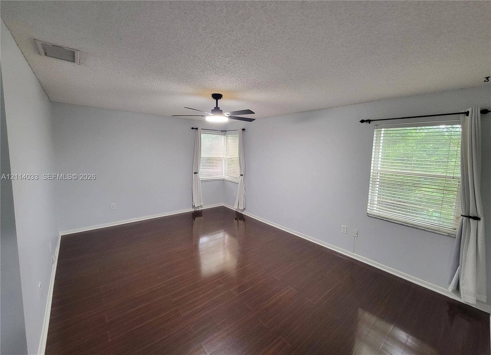 683 NW 88th Drive, Coral Springs, Coral Springs, FL 33071 Interior space featuring dark wood-finish flooring, a ceiling fan with integrated lighting, dual-window corner configuration, and horizontal window blinds