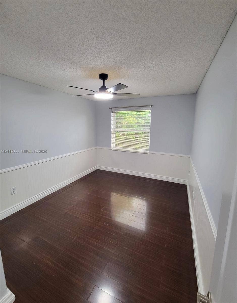 683 NW 88th Drive, Coral Springs, Coral Springs, FL 33071 Room featuring wood-finish flooring, white wainscoting, a single-hung window, and an integrated ceiling fan with light fixture