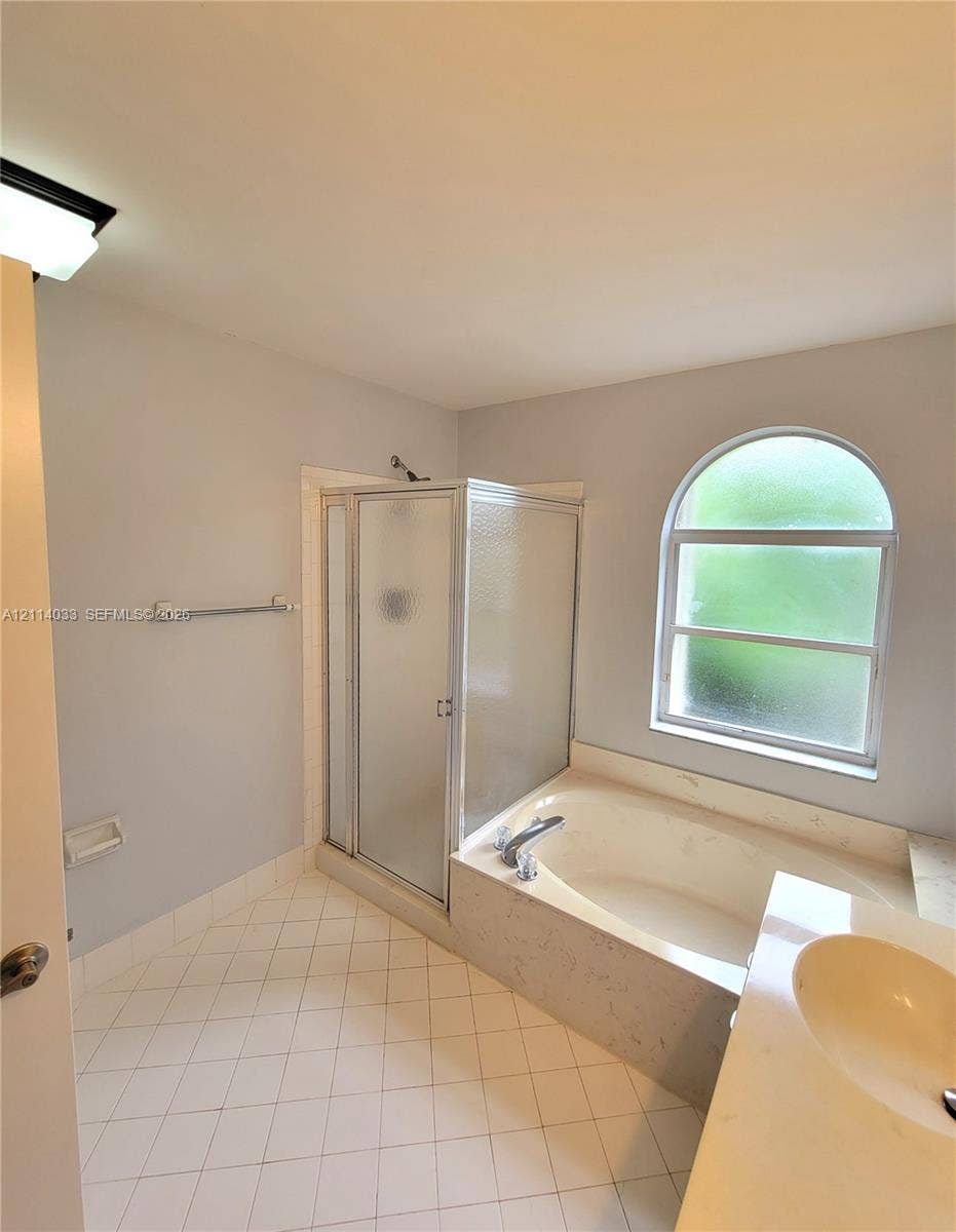 683 NW 88th Drive, Coral Springs, Coral Springs, FL 33071 Bathroom featuring a soaking tub, separate glass-enclosed shower, arched window, and tile flooring