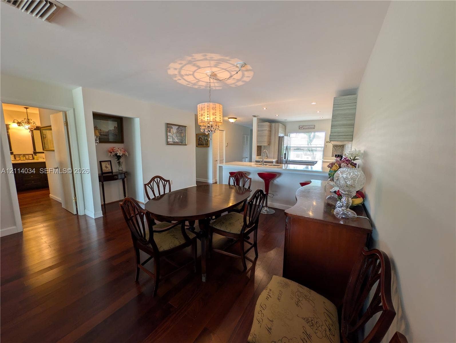 8460 Casa Del Lago, #H, Boca Raton, Boca Raton, FL 33433 Dining area featuring wood-finish flooring, a decorative crystal-style chandelier, and a breakfast bar with stone-finish countertops
