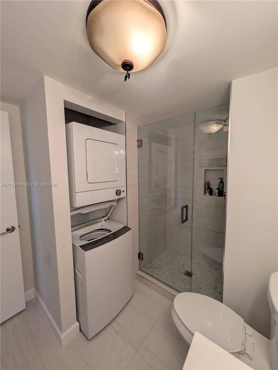 8460 Casa Del Lago, #H, Boca Raton, Boca Raton, FL 33433 Walk-in shower featuring a glass enclosure, pebble-stone flooring, and a tiled wall niche, paired with a recessed laundry closet and overhead dome lighting