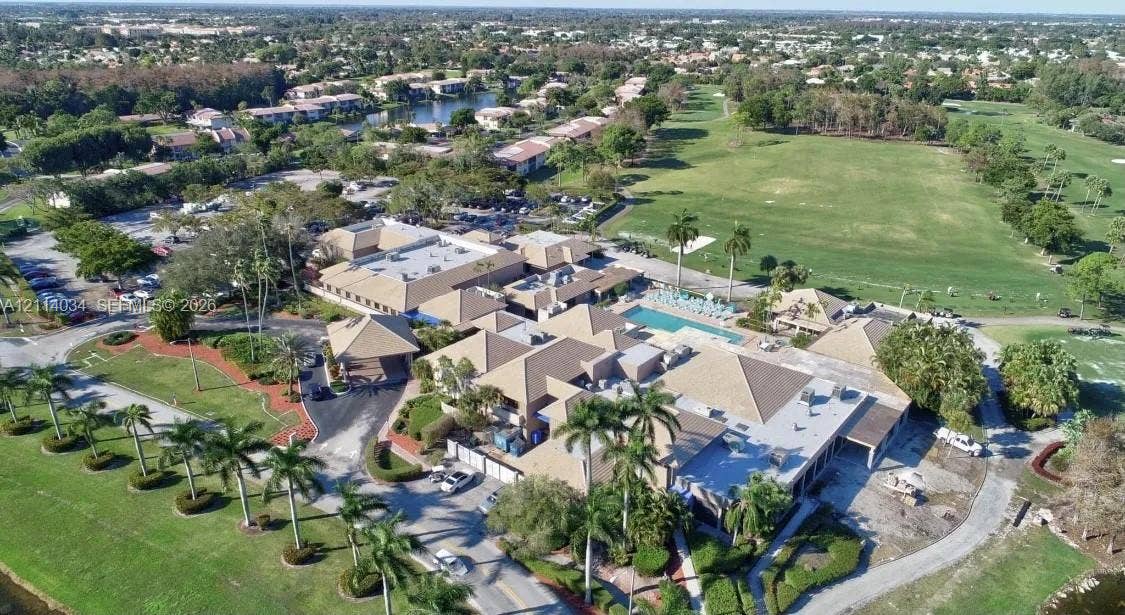 8460 Casa Del Lago, #H, Boca Raton, Boca Raton, FL 33433 Aerial perspective featuring a multi-wing complex with pitched rooflines, an outdoor swimming pool, and extensive grounds with mature palm trees