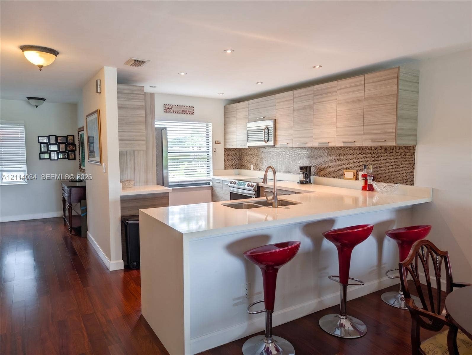 8460 Casa Del Lago, #H, Boca Raton, Boca Raton, FL 33433 Kitchen featuring wood-finish cabinetry, quartz countertops, mosaic tile backsplash, stainless steel appliances, and wood-finish flooring