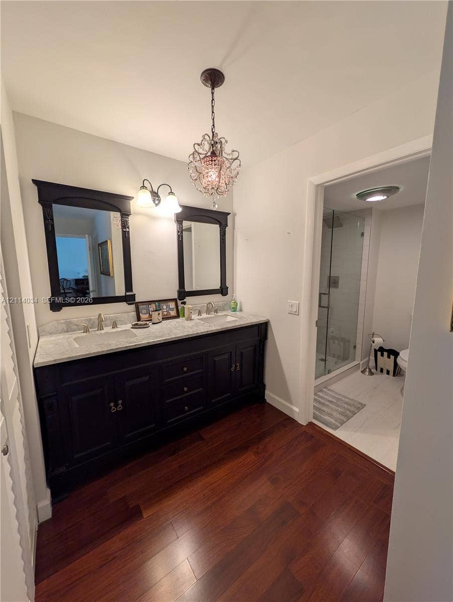 8460 Casa Del Lago, #H, Boca Raton, Boca Raton, FL 33433 Double vanity featuring a dark-finish wood cabinet, stone-surface countertop, dual drop-in sinks, and a decorative crystal-style pendant fixture