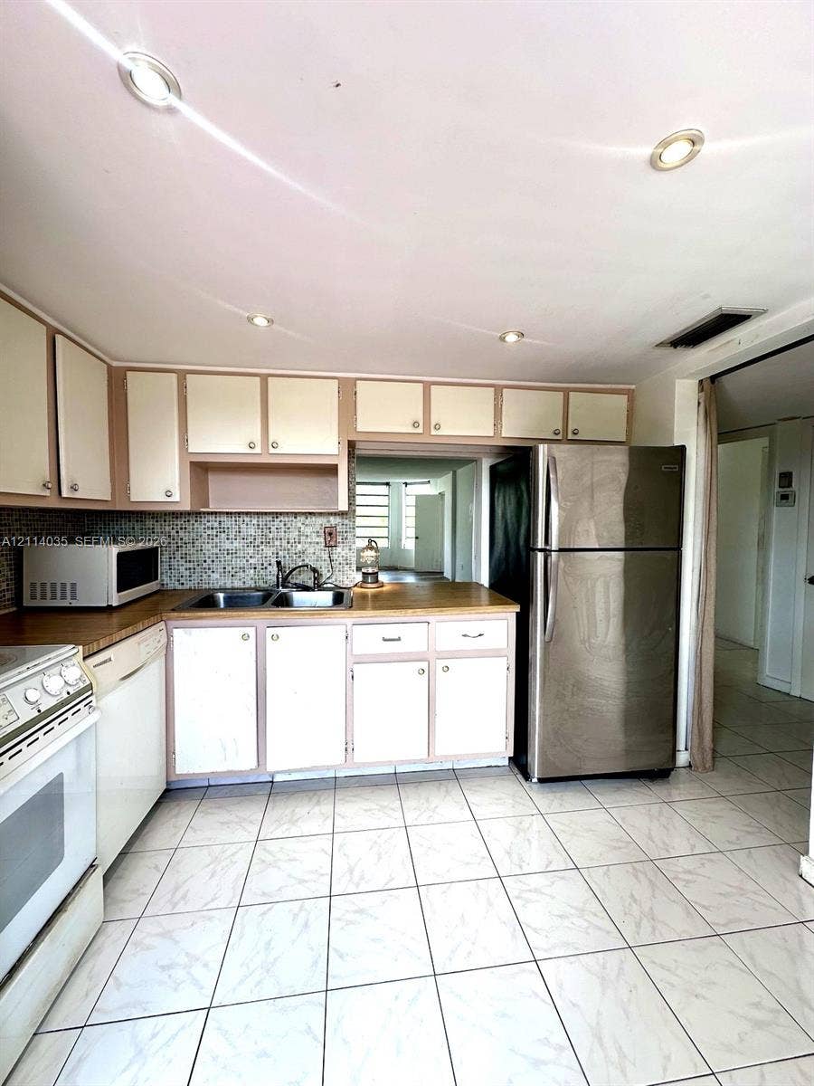 1501 NE 191st Street, #C312, Miami, Miami, FL 33179 Kitchen featuring solid-surface countertops, mosaic tile backsplash, stainless steel refrigerator, recessed lighting, and tile flooring