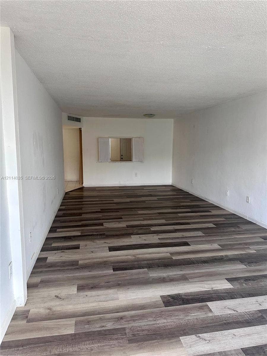 1501 NE 191st Street, #C312, Miami, Miami, FL 33179 Interior space featuring multi-tonal wood-finish flooring, neutral walls, and a cutout wall pass-through