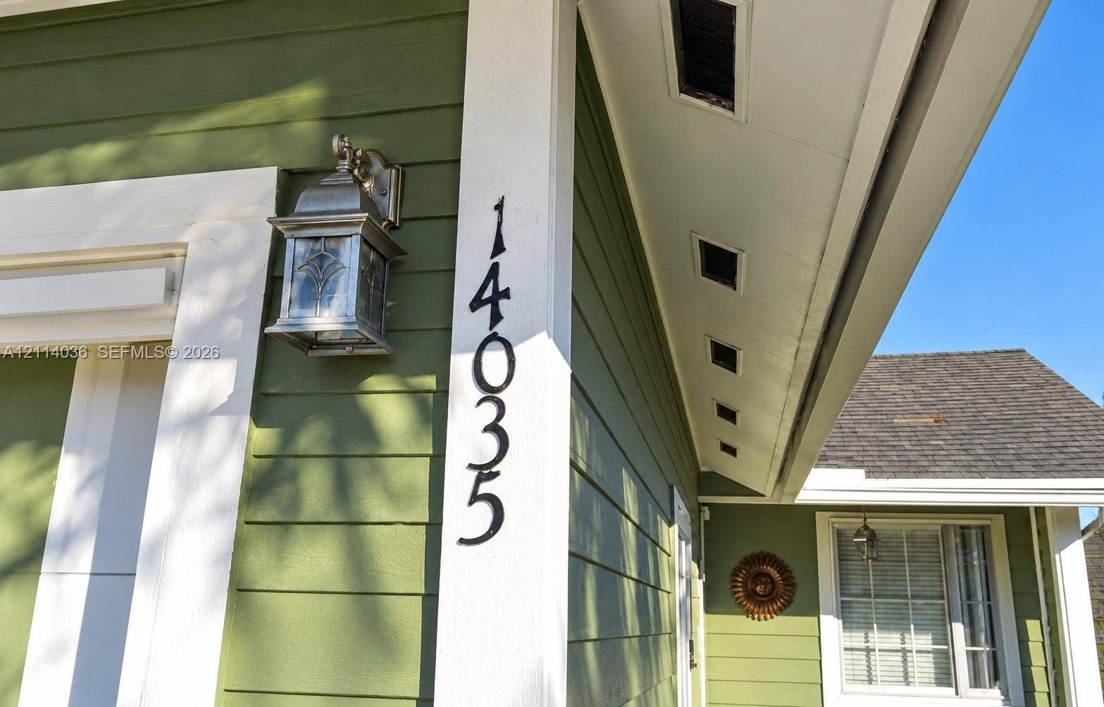 14035 SW 103rd Terrace, Miami, FL 33186 Exterior elevation featuring sage green horizontal lap siding, white trim, custom metal wall-mounted lantern, and high-contrast vertical house numbering
