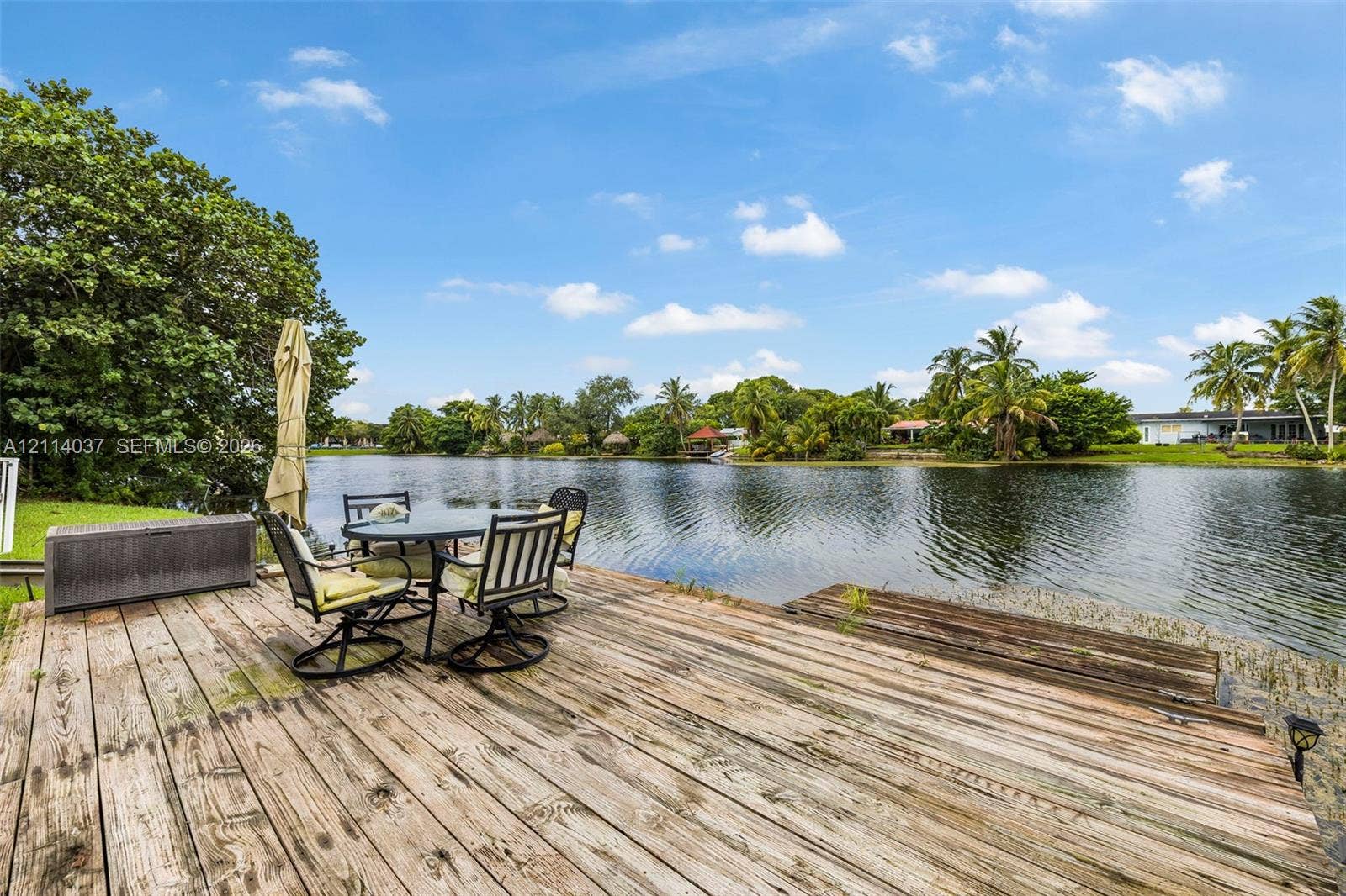 8436 SW 143rd Avenue, Miami, FL 33183 Waterfront wooden deck featuring plank decking, direct water access, and mature landscaping