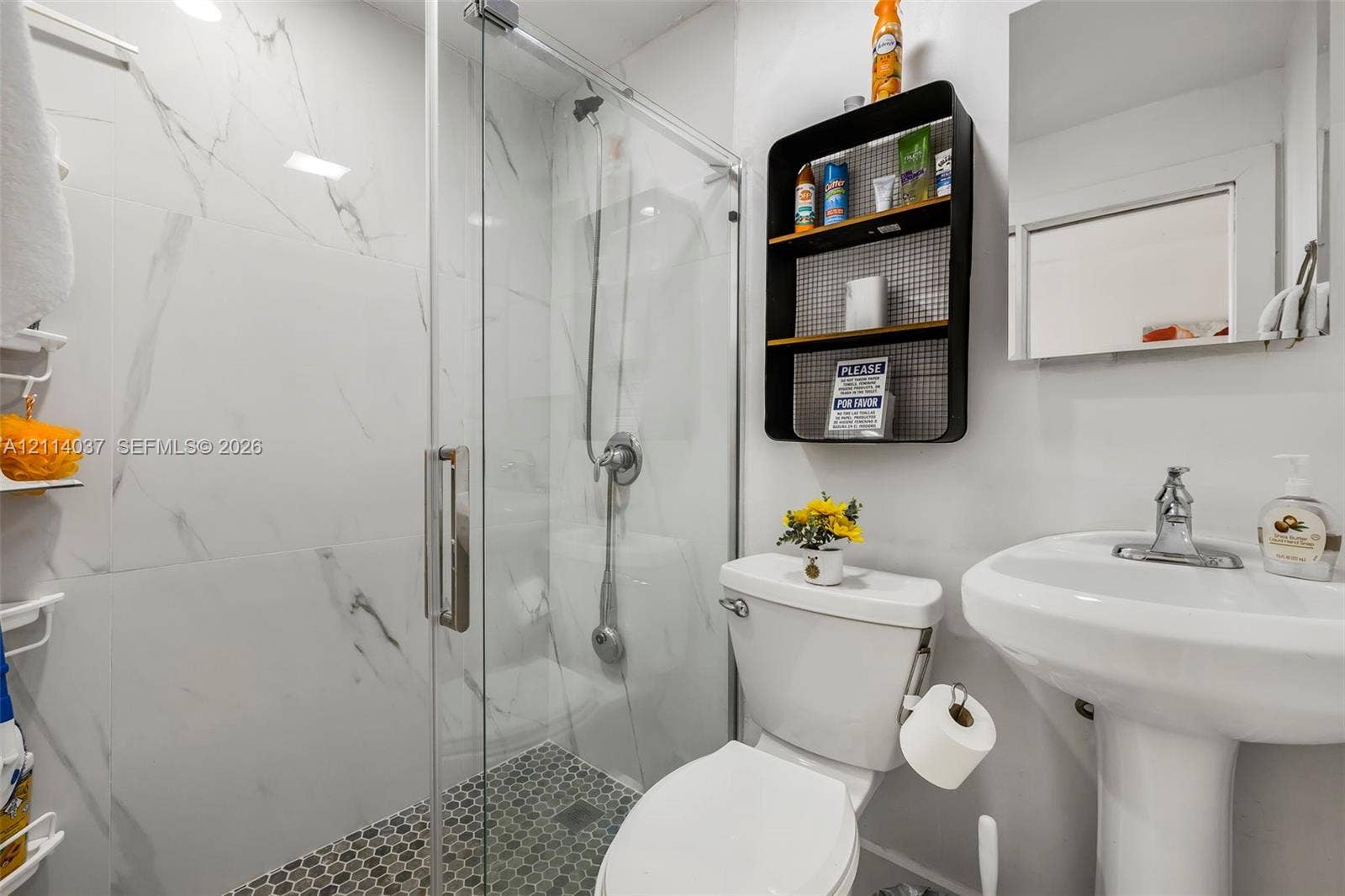 8436 SW 143rd Avenue, Miami, FL 33183 Walk-in glass shower with floor-to-ceiling large-format stone-finish tiling, hexagonal mosaic tile shower flooring, and pedestal sink