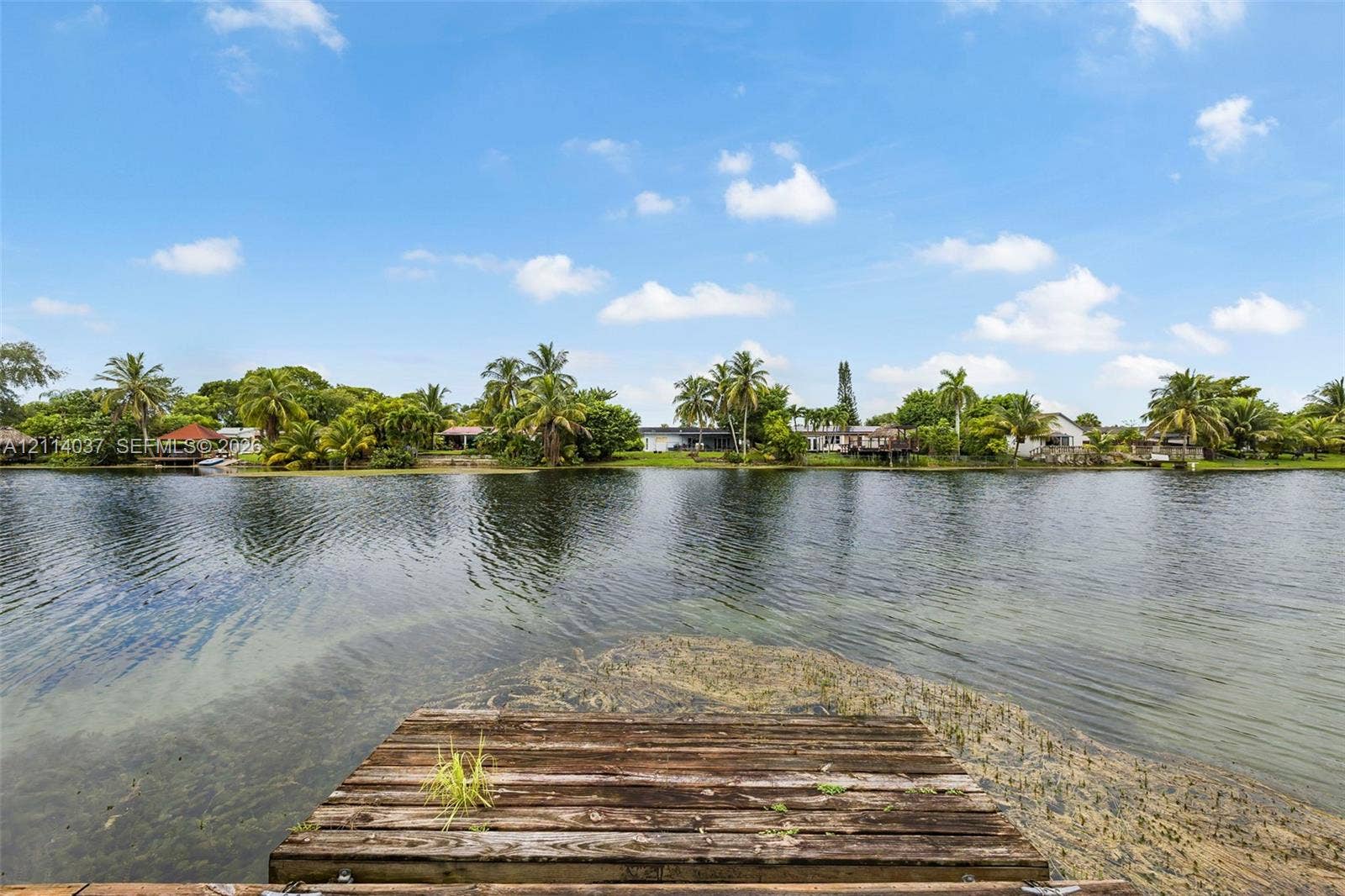 8436 SW 143rd Avenue, Miami, FL 33183 Waterfront property featuring a wooden dock, expansive canal, and lush tropical landscaping
