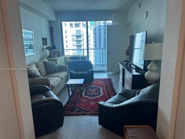 Floor-to-ceiling windows, wood-finish flooring, and an attached balcony