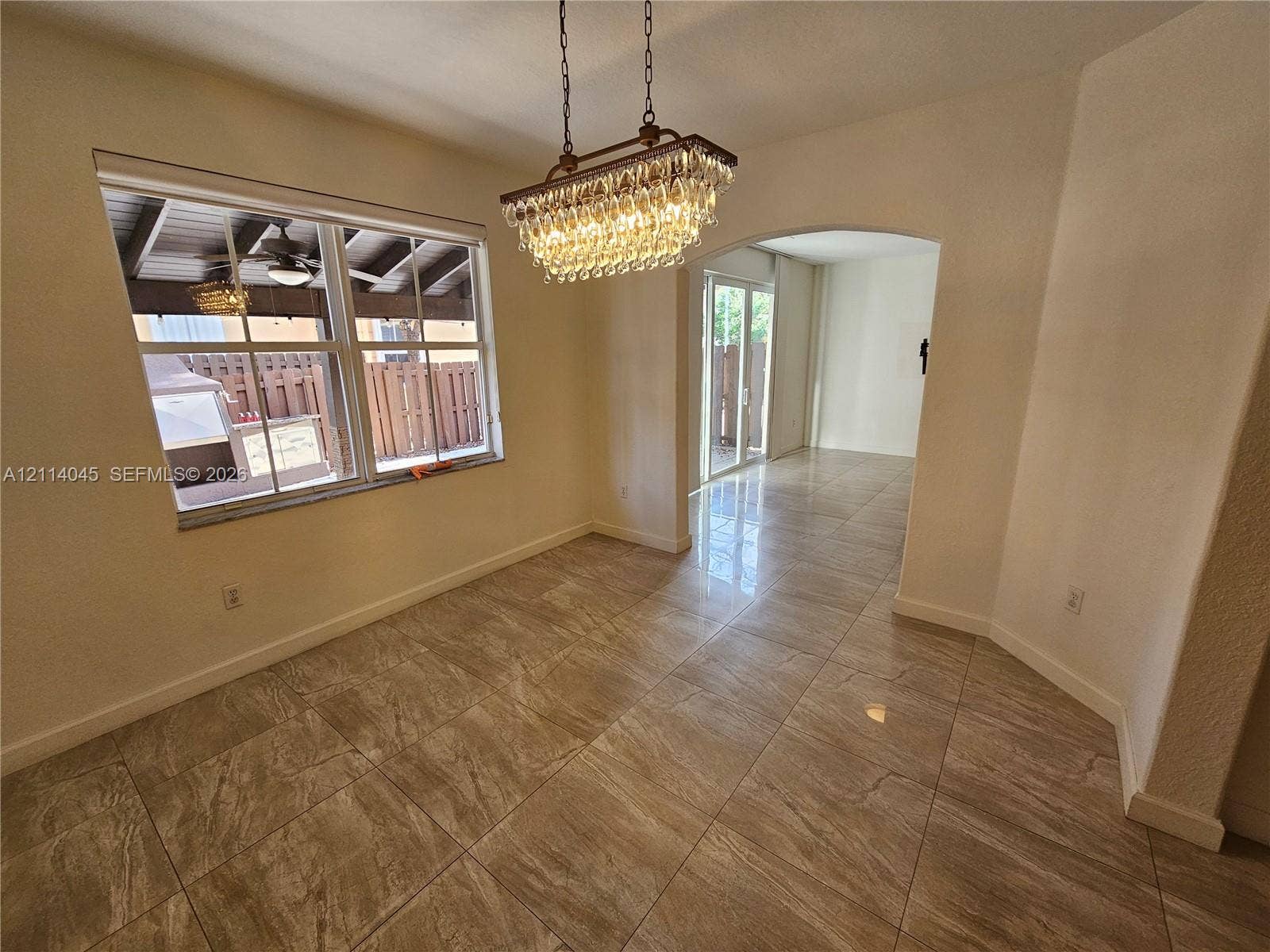 Stone-finish tile flooring, decorative multi-tier crystal chandelier, arched entryway, and double-pane window