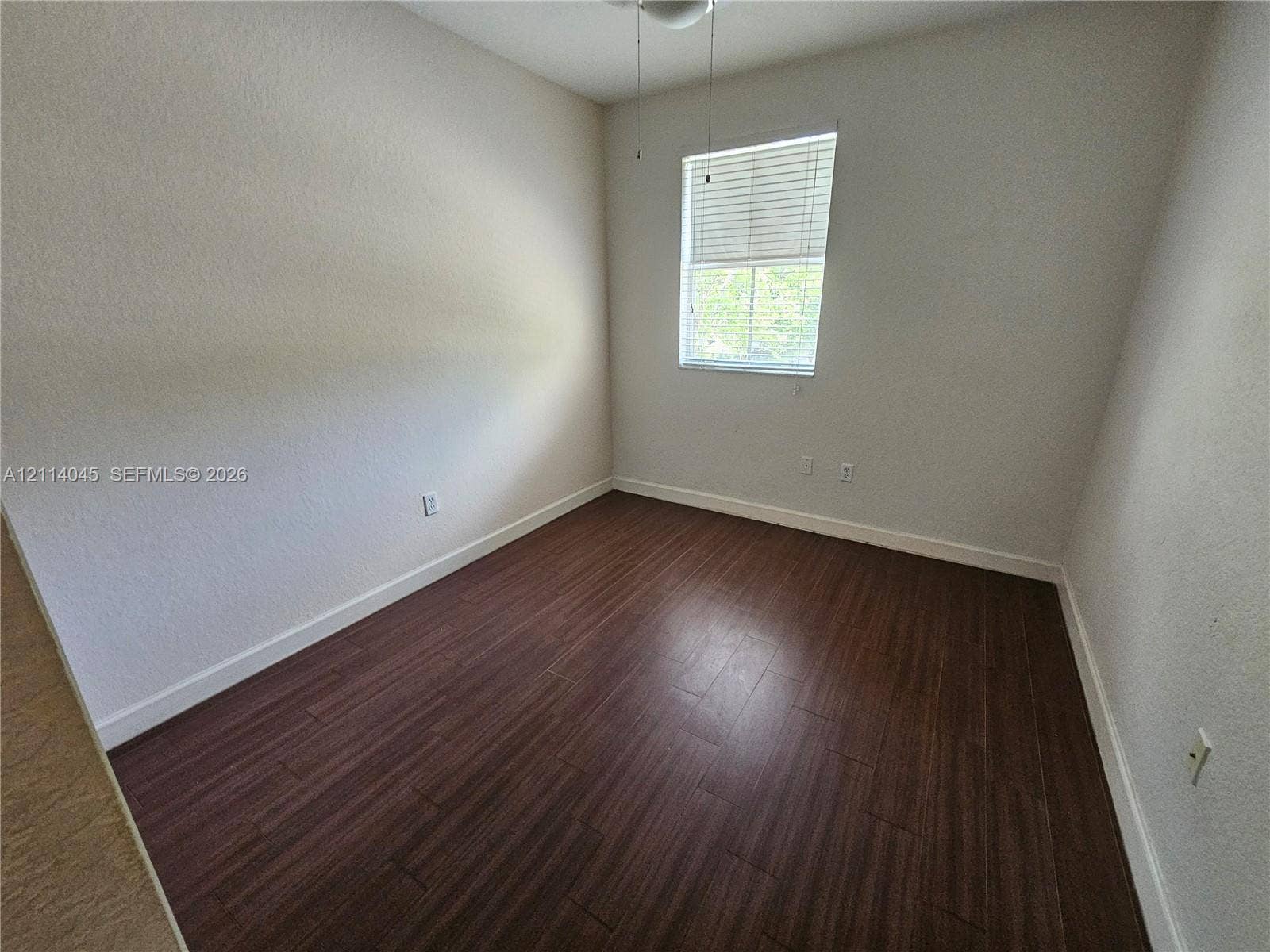 Room featuring wood-finish flooring, a single-pane window with horizontal blinds, and an attached ceiling fan