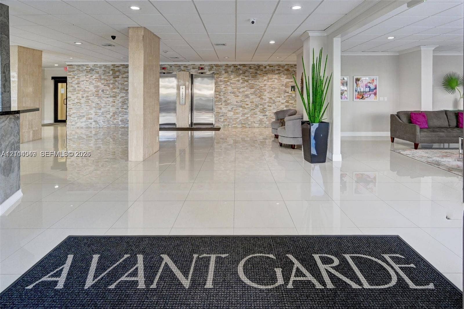 Lobby featuring polished tile flooring, stacked stone wall accents, brushed metal elevator doors, and recessed ceiling lighting