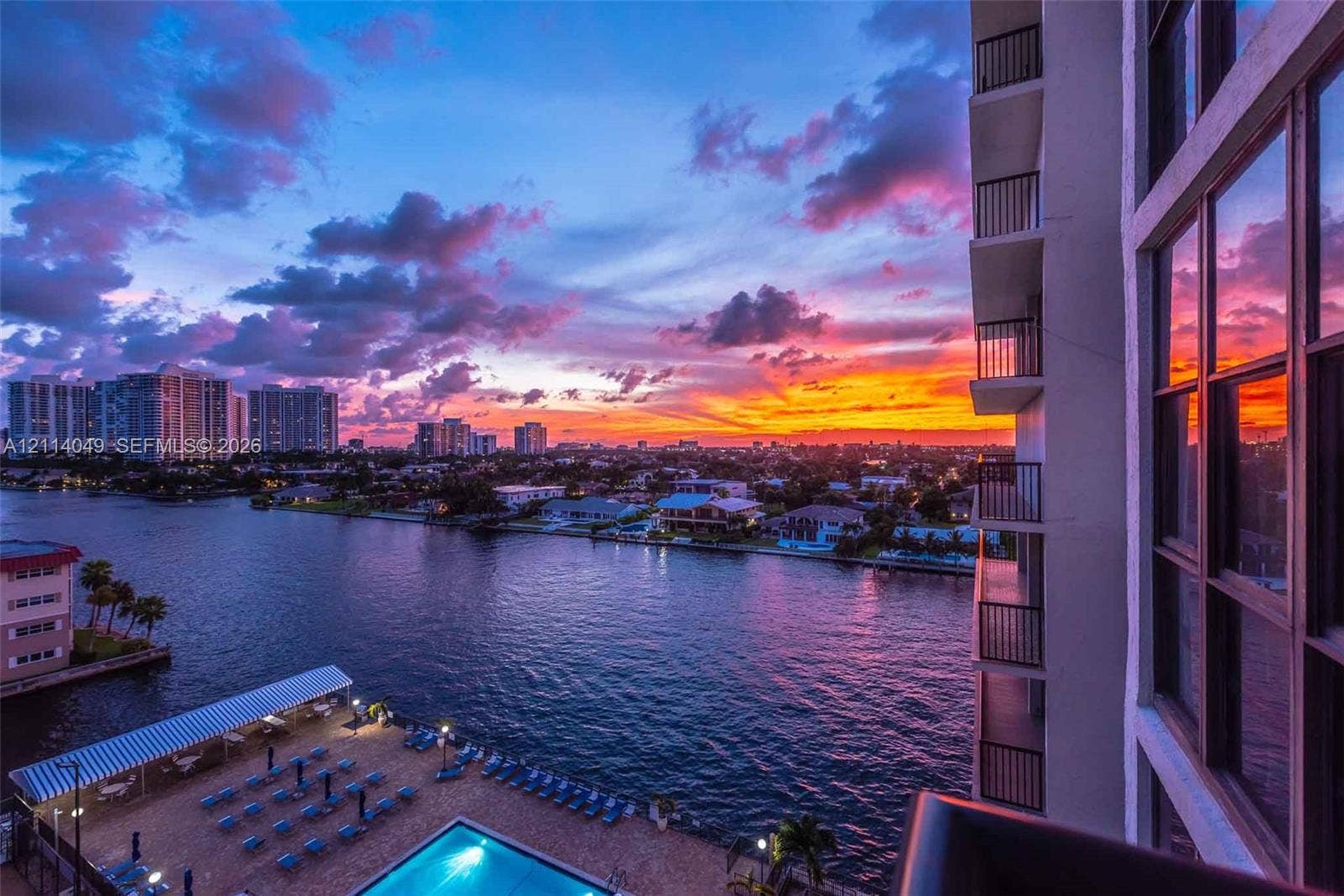 Waterfront high-rise building featuring private balconies with view of swimming pool, intracoastal and expansive skyline sunset views