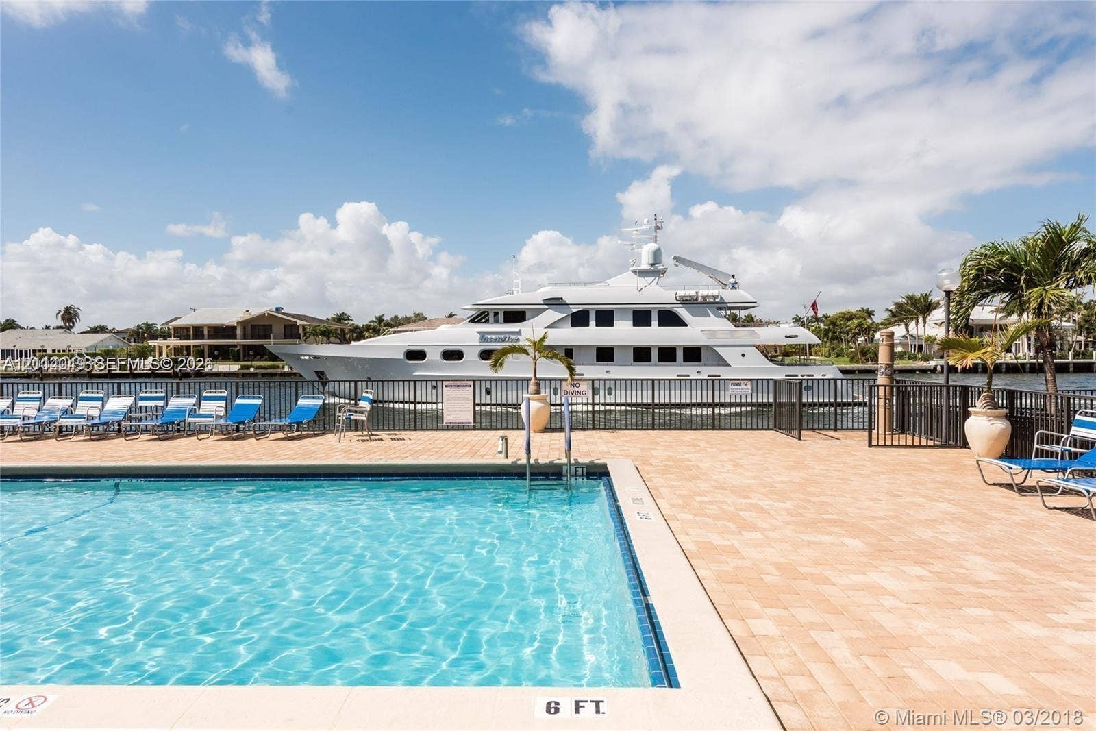 Swimming pool with a paved deck, black metal fencing, and water frontage