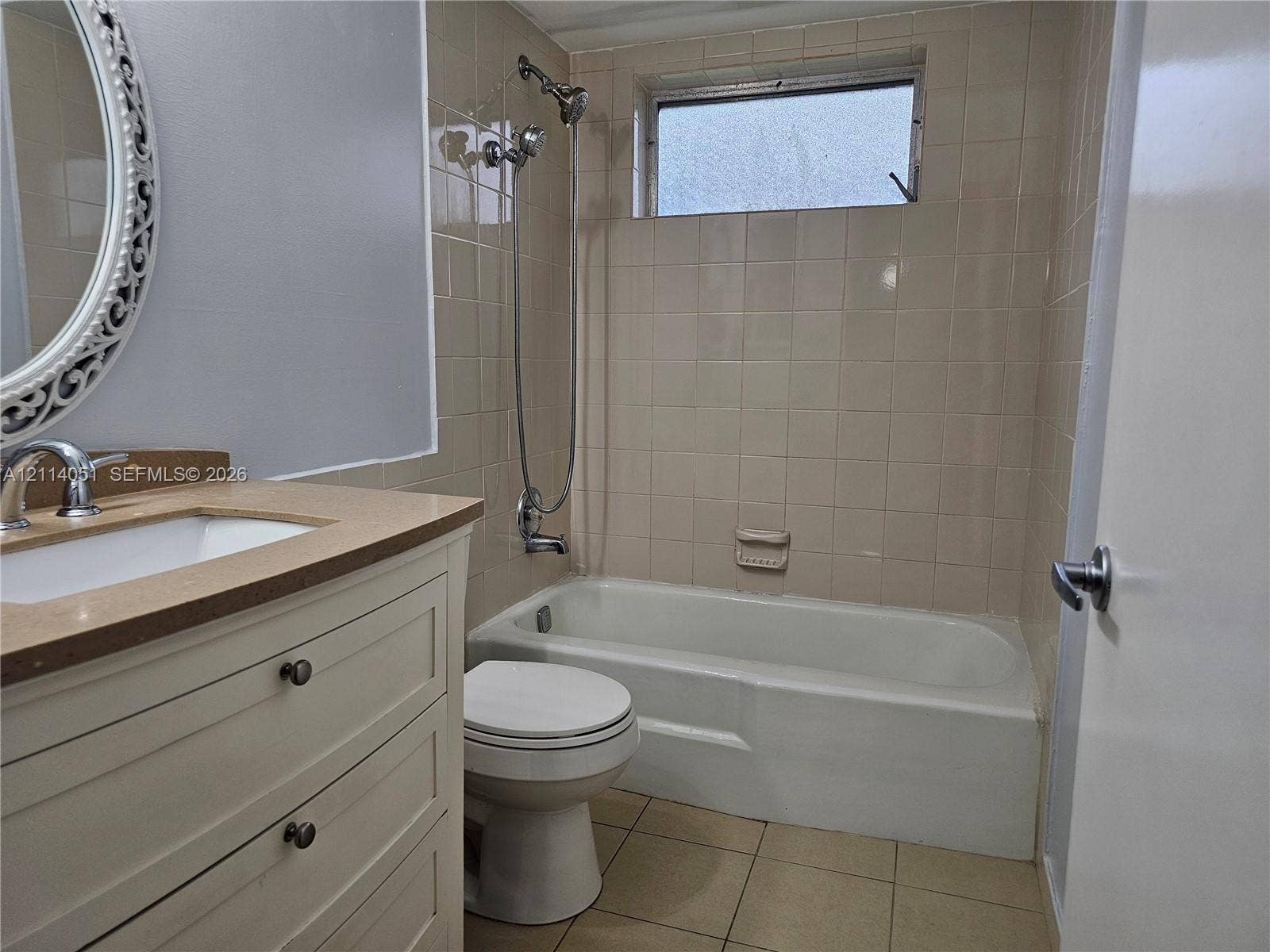 2431 SW 82nd Avenue, #102, Davie, FL 33324 Bathroom featuring a vanity with a solid-surface countertop, an integrated sink, a built-in tub with a wall-mounted shower fixture, ceramic tile surround, and an inset window
