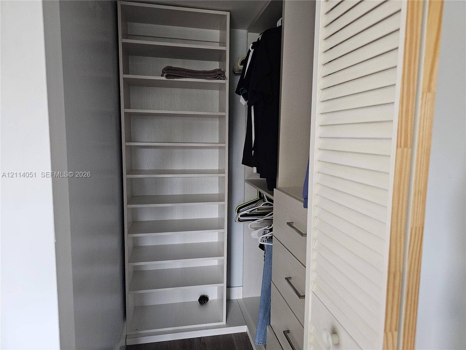2431 SW 82nd Avenue, #102, Davie, FL 33324 Custom closet organization system featuring vertical shelving, hanging rods, built-in drawers with horizontal bar pulls, and a louvered door