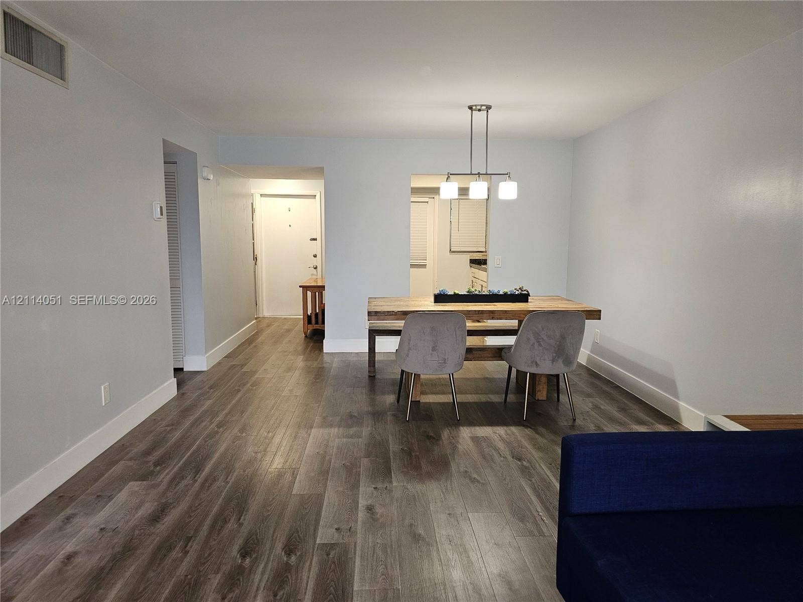 2431 SW 82nd Avenue, #102, Davie, FL 33324 Open-concept interior featuring wood-finish flooring, neutral wall paint, and a modern three-light pendant fixture