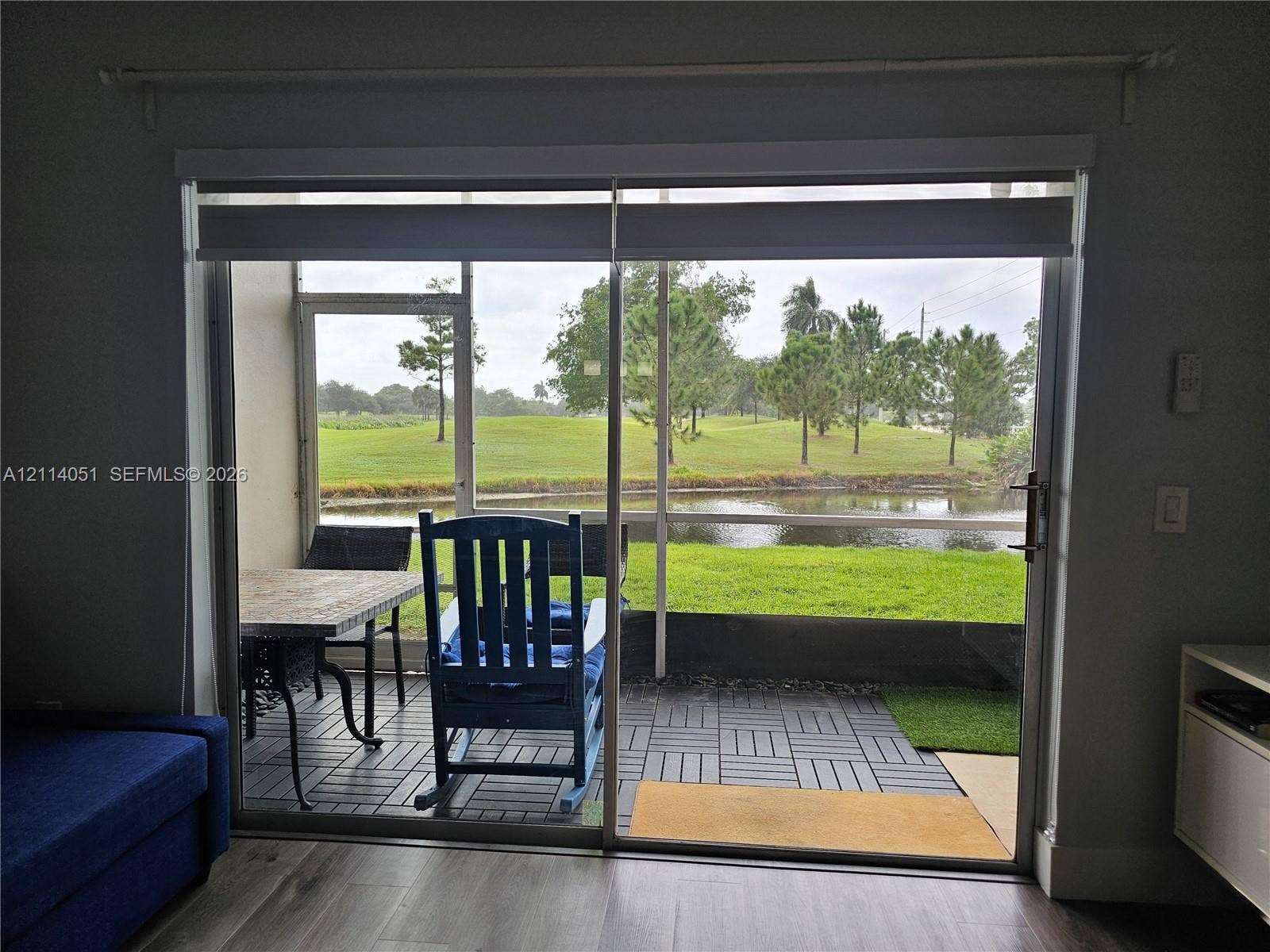 2431 SW 82nd Avenue, #102, Davie, FL 33324 Sliding glass door opening to a screened-in patio featuring modular tile flooring, overlooking a pond and landscape