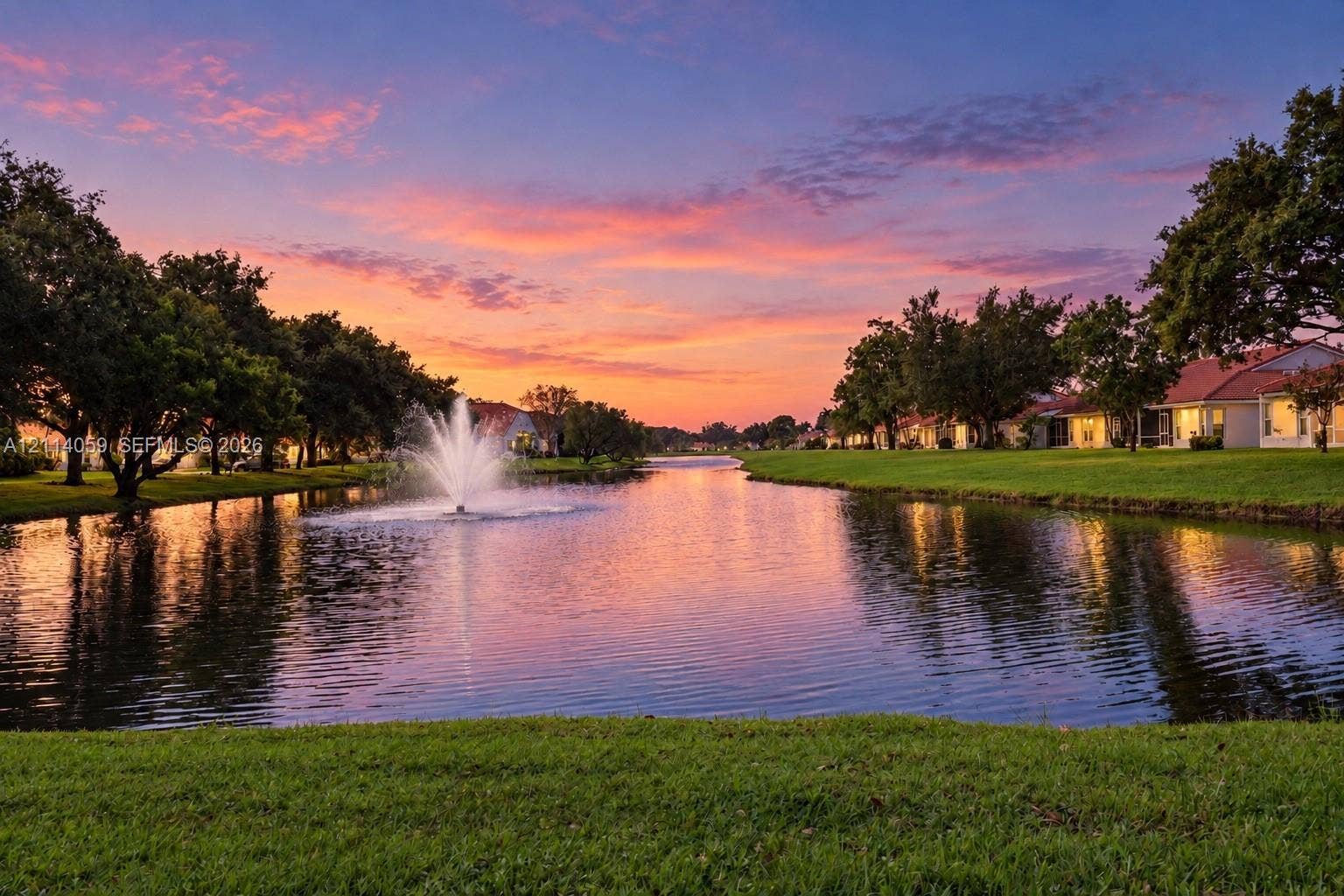 8023 N Tranquility Lake Drive, Delray Beach, FL 33446 Waterfront pond featuring a central fountain, manicured lawn, and mature trees