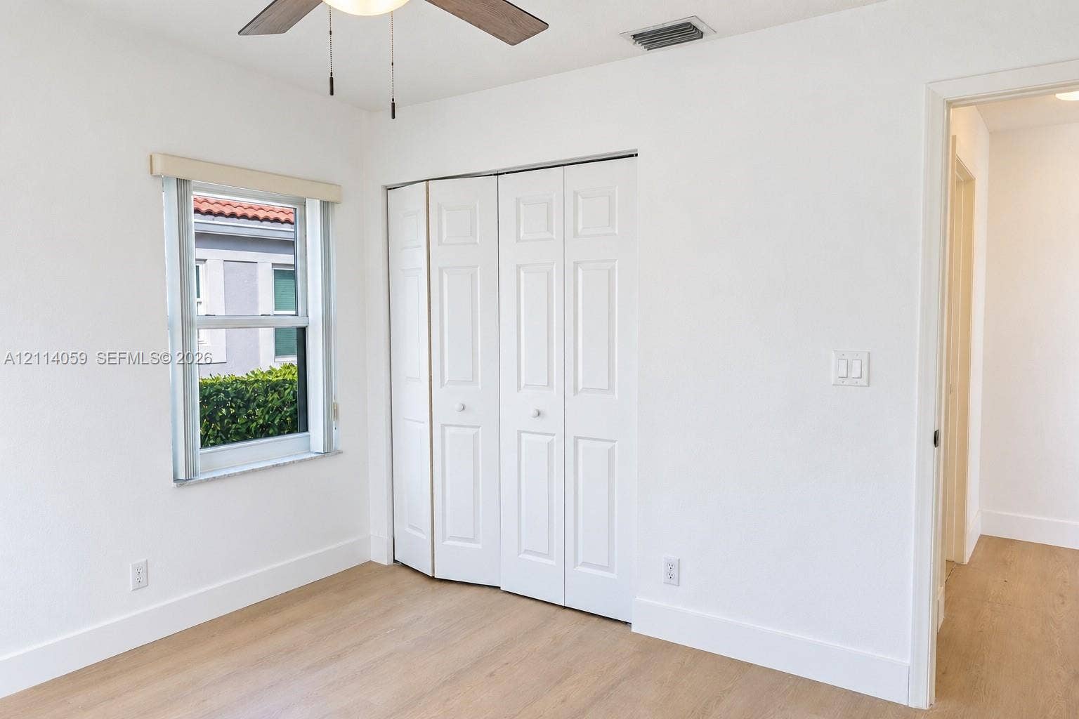 8023 N Tranquility Lake Drive, Delray Beach, FL 33446 Wood-finish flooring, white paneled bifold closet doors, and a ceiling fan with integrated lighting