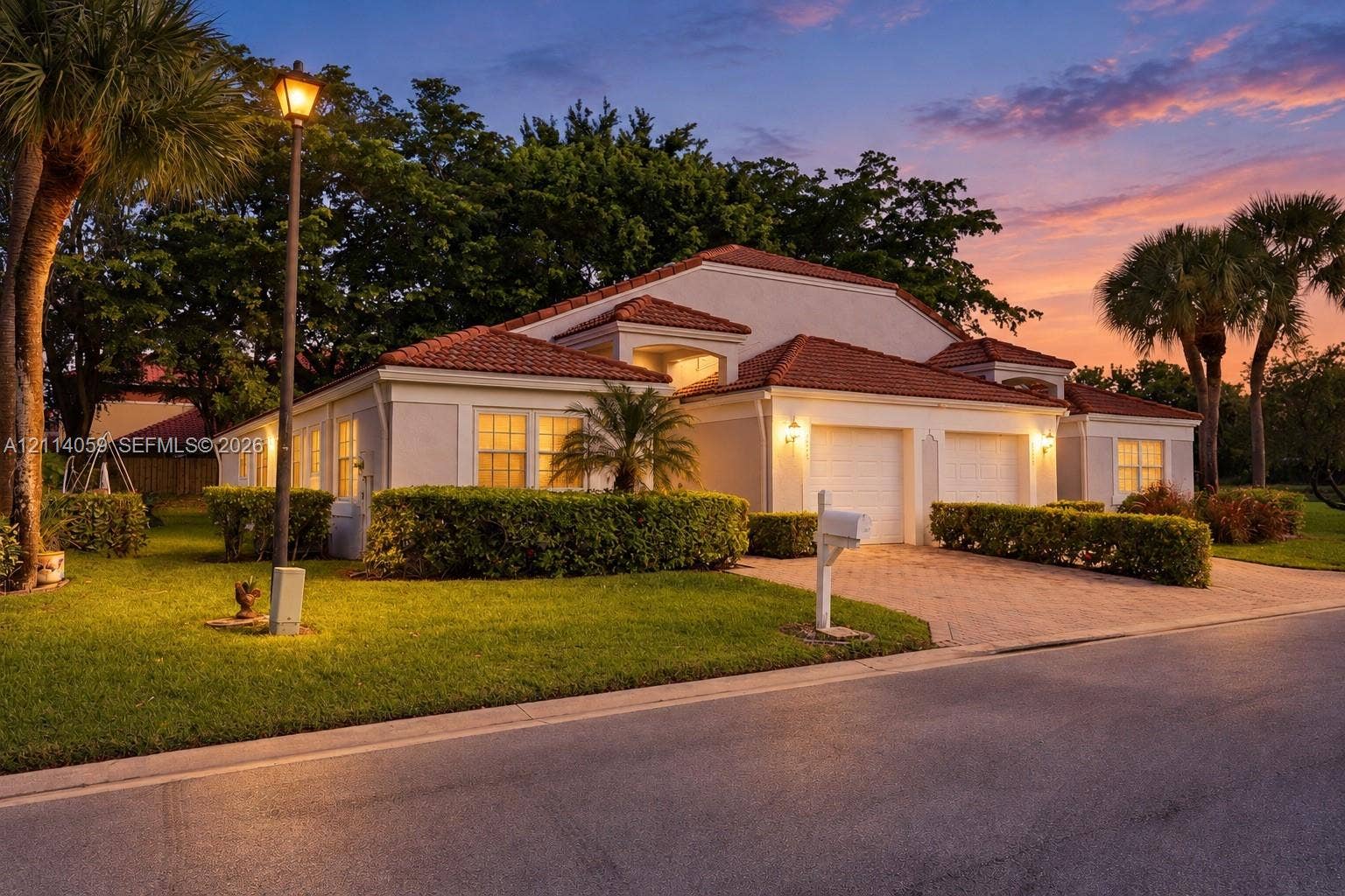 8023 N Tranquility Lake Drive, Delray Beach, FL 33446 Stucco exterior featuring a multi-gabled terracotta tile roof, two-car garage, and paver driveway