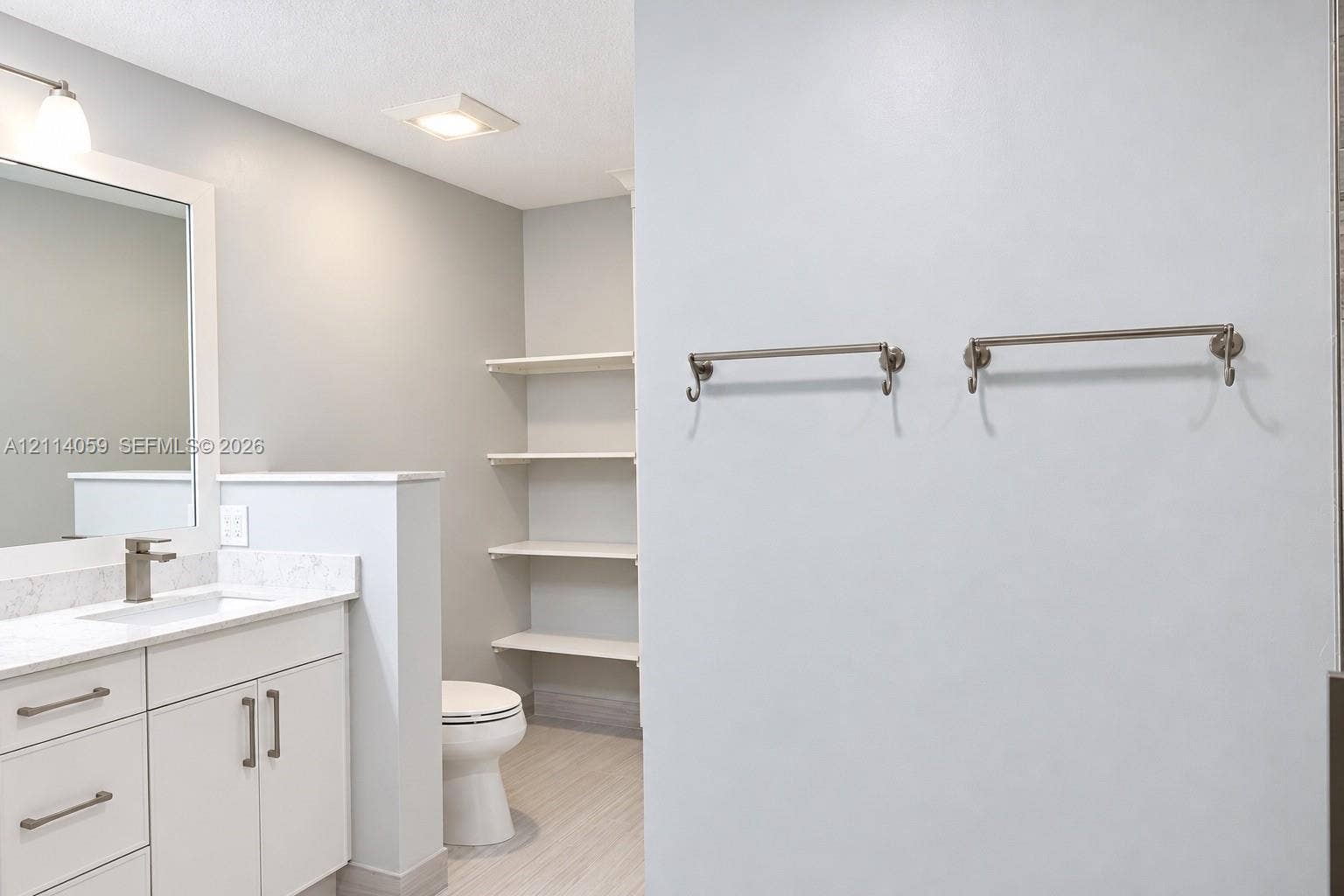8023 N Tranquility Lake Drive, Delray Beach, FL 33446 Bathroom featuring white cabinetry, stone-finish vanity countertop, undermount sink, built-in wall shelving, and dual brushed-nickel towel bars