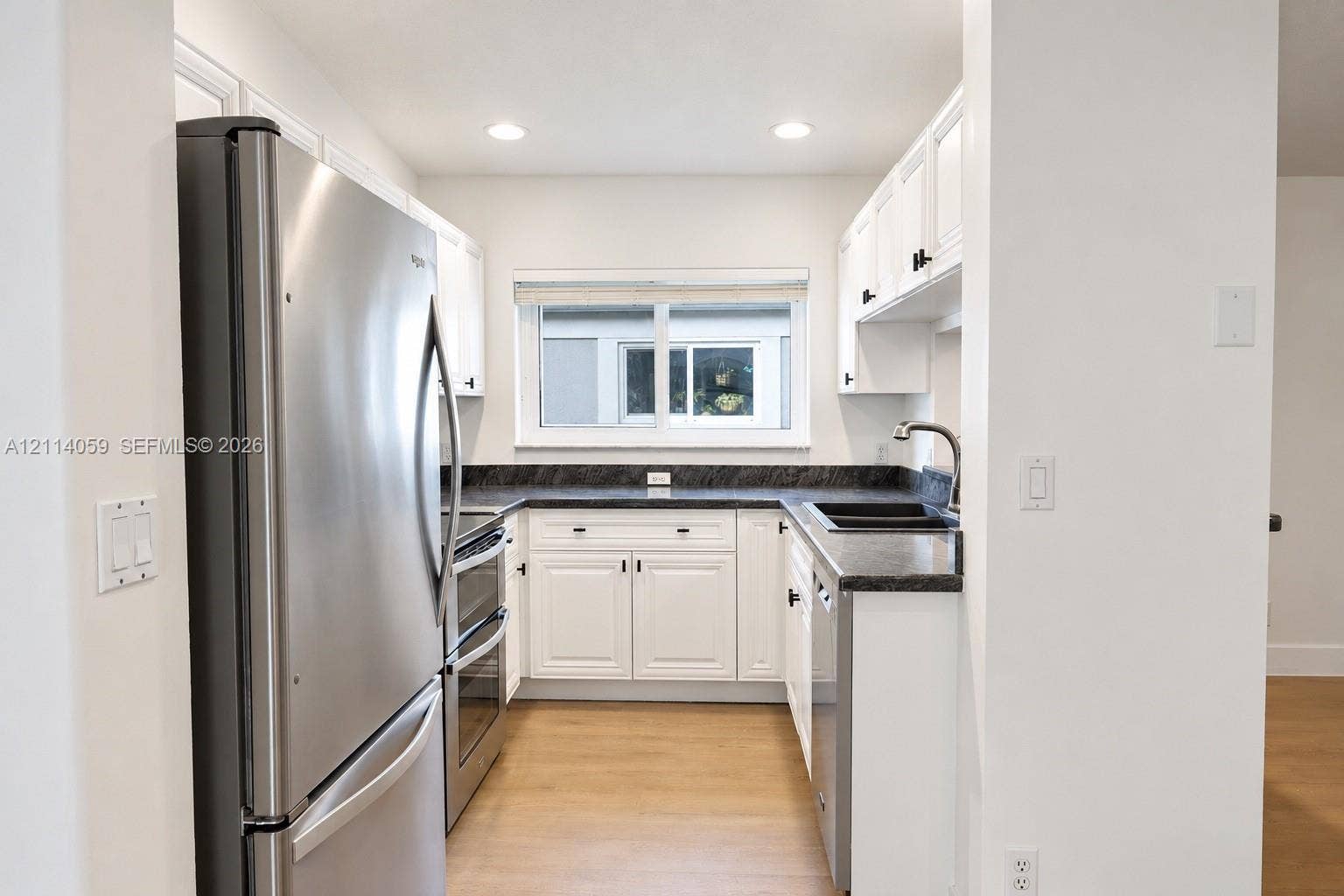 8023 N Tranquility Lake Drive, Delray Beach, FL 33446 Kitchen featuring white shaker-style cabinetry, dark stone-finish countertops, stainless steel appliances, and wood-finish flooring