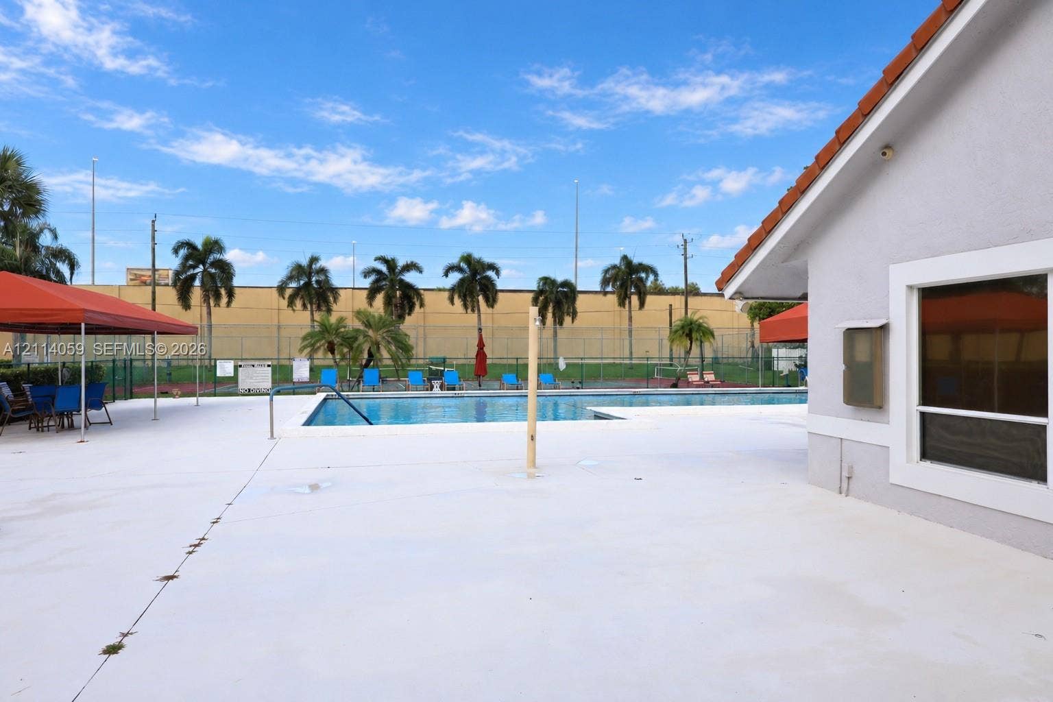 8023 N Tranquility Lake Drive, Delray Beach, FL 33446 Outdoor pool area featuring a concrete deck, metal perimeter fencing, and palm tree landscaping