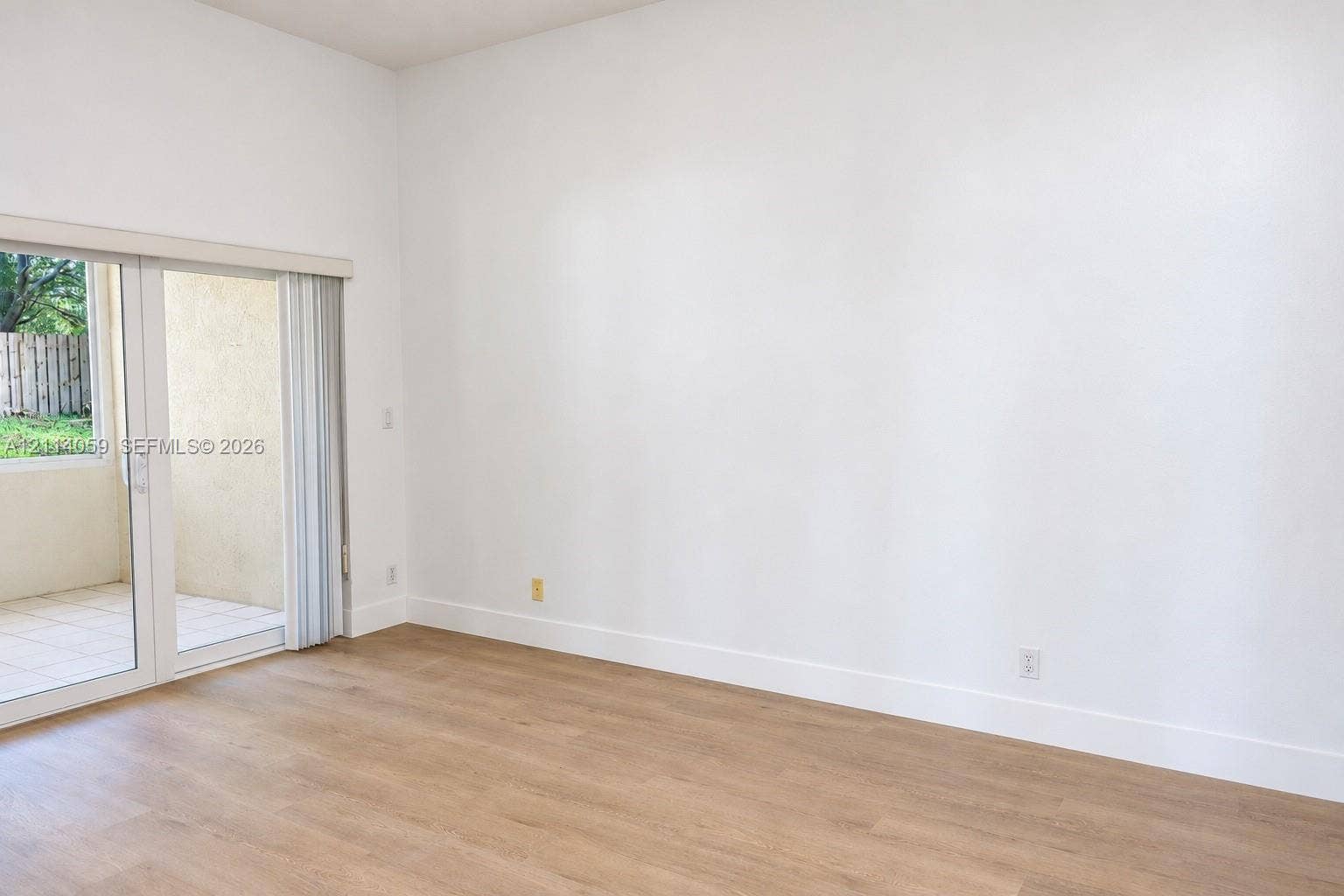 8023 N Tranquility Lake Drive, Delray Beach, FL 33446 High ceilings, wood-finish flooring, and glass sliding doors with vertical blinds