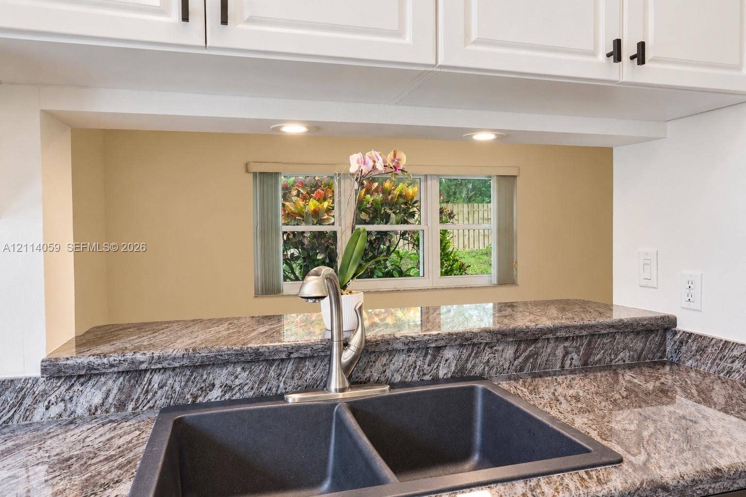 8023 N Tranquility Lake Drive, Delray Beach, FL 33446 Kitchen featuring stone-finish countertops, undermount double-basin sink, high-arch faucet, white cabinetry with matte black hardware, and recessed lighting
