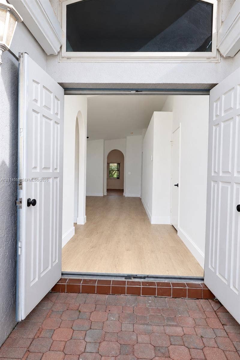 8023 N Tranquility Lake Drive, Delray Beach, FL 33446 Double front entry doors with transom window, wood-finish flooring, and arched interior doorways