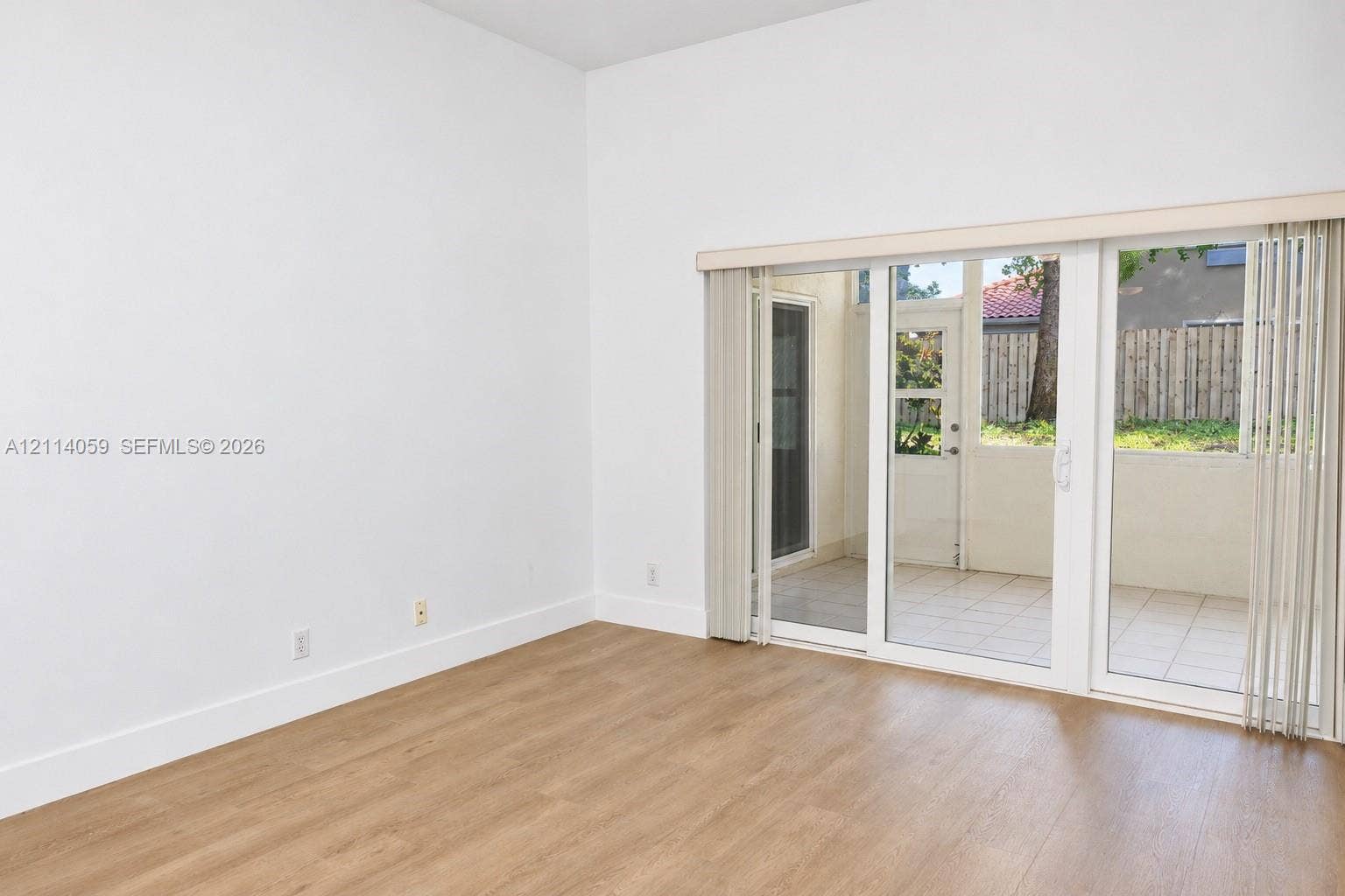8023 N Tranquility Lake Drive, Delray Beach, FL 33446 Room with wood-finish flooring and sliding glass doors opening to a tiled exterior patio