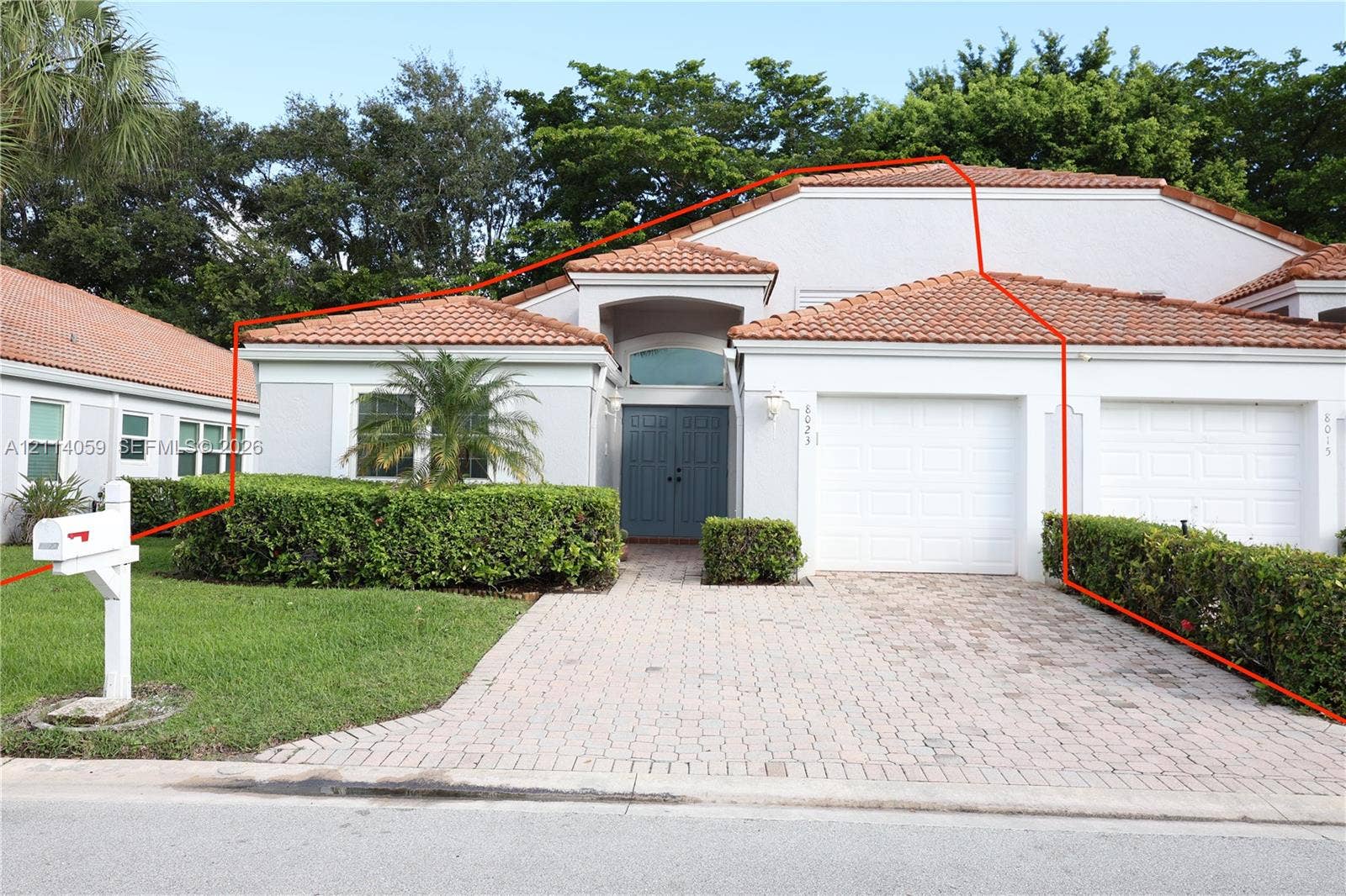 8023 N Tranquility Lake Drive, Delray Beach, FL 33446 Stucco exterior featuring a clay tile roof, double-door entry with arched transom window, paved driveway, and attached two-car garage