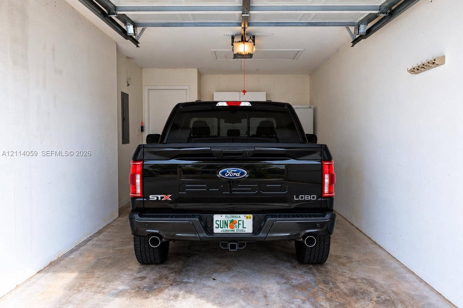 8023 N Tranquility Lake Drive, Delray Beach, FL 33446 Enclosed garage featuring concrete flooring, a motorized overhead door system, ceiling-mounted light fixture, and interior access door