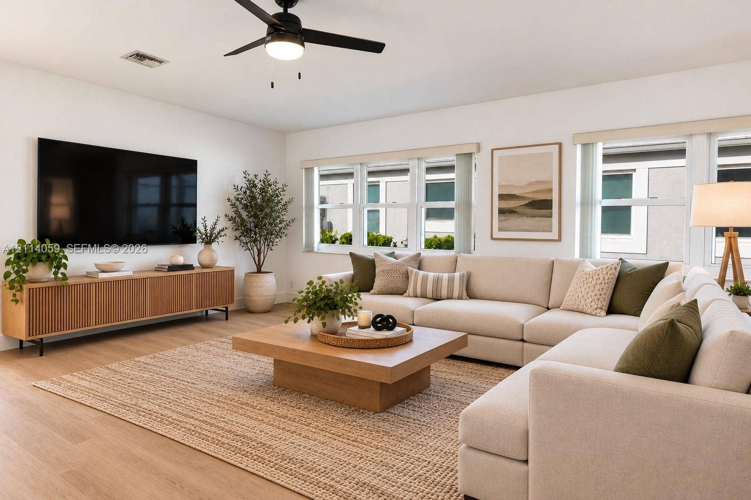 8023 N Tranquility Lake Drive, Delray Beach, FL 33446 Living area featuring wood-finish flooring, matte black ceiling fan with integrated lighting, neutral wall palette, and expansive multi-pane window configuration