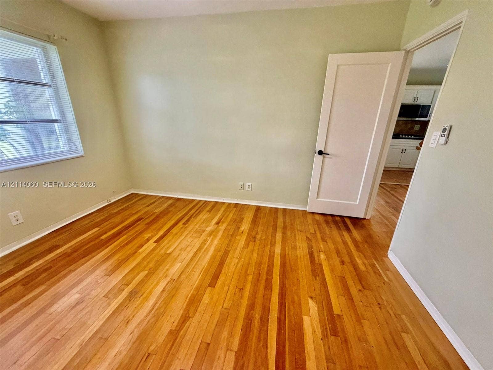 2325 Fillmore Street, #1, Hollywood, Hollywood, FL 33020 Room featuring wood-finish flooring, a single-panel interior door, and a window with horizontal blinds