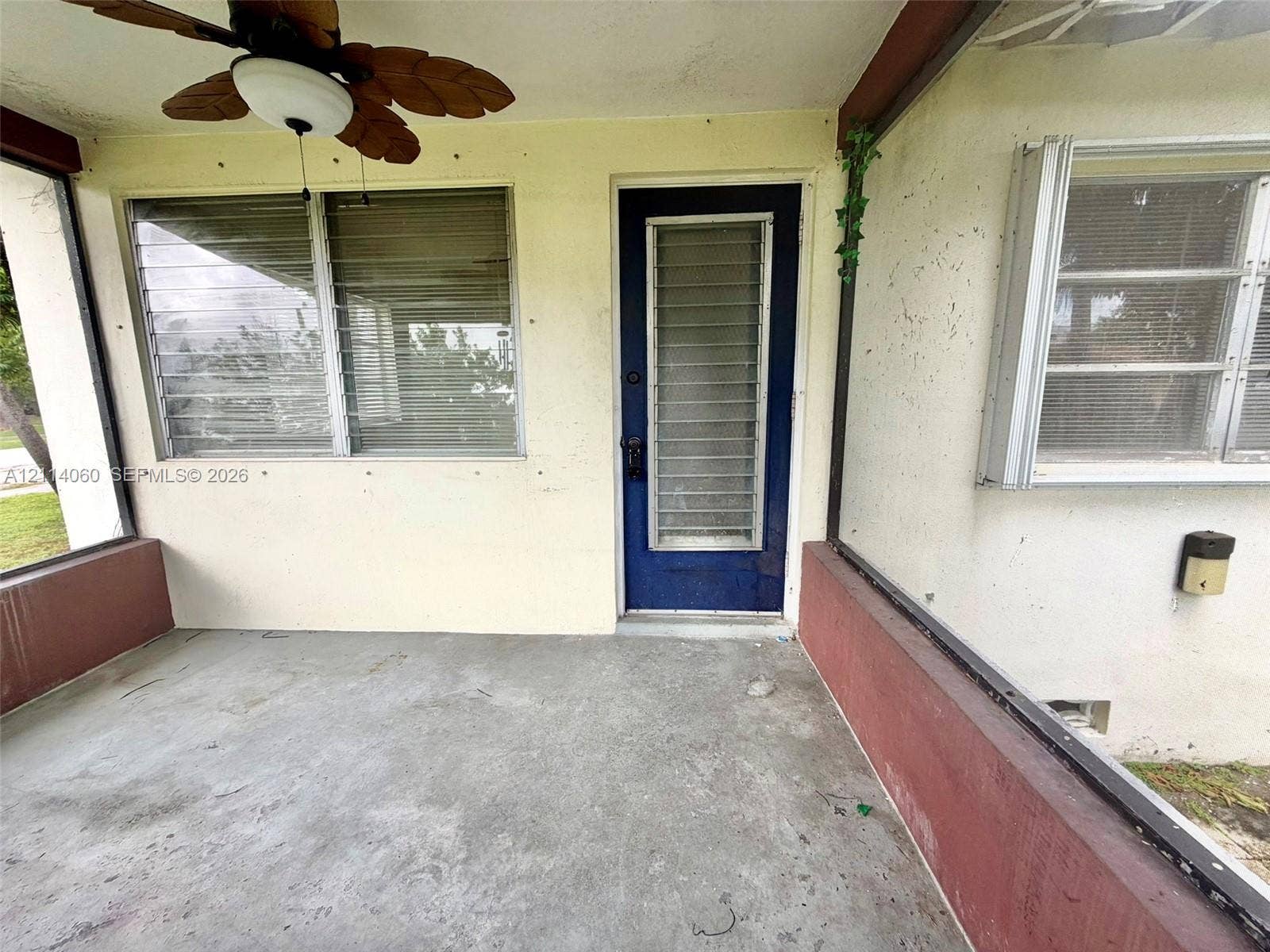 2325 Fillmore Street, #1, Hollywood, Hollywood, FL 33020 Screened-in porch featuring a concrete floor, ceiling fan with palm-leaf style blades, louvered windows, and a metal-frame entrance door with integrated ventilation slats