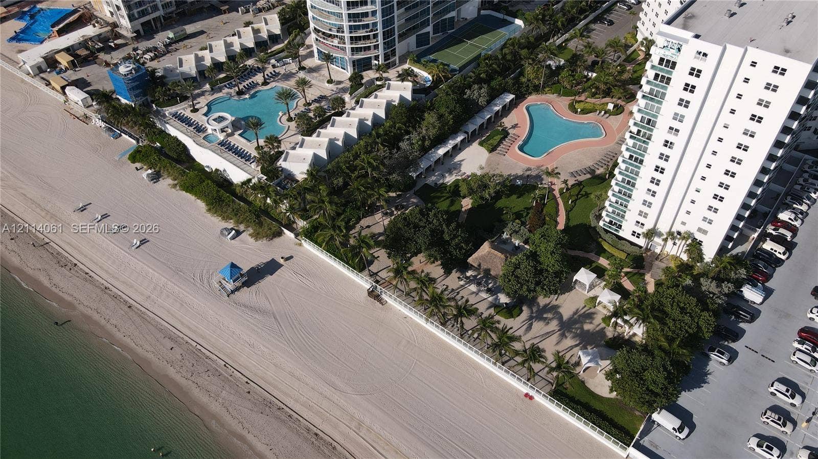 3001 S Ocean Drive, #727, Hollywood, FL 33019 Aerial perspective of beachfront property featuring direct ocean access, multiple swimming pools, lush landscaped grounds with mature palm trees, and gated perimeters