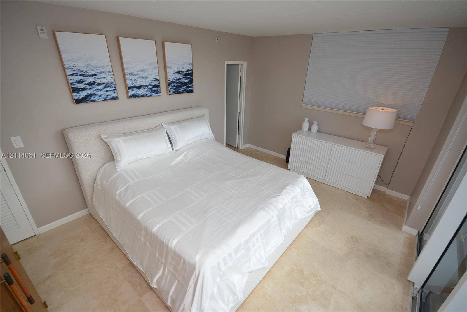 3001 S Ocean Drive, #727, Hollywood, FL 33019 Neutral-toned walls with natural stone tile flooring, oversized window featuring a retractable cellular shade, and a door with louvered shutter detail