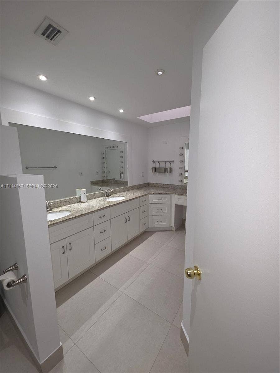 Weston, Weston, FL 33326 Bathroom featuring a dual-sink vanity with stone countertops, white cabinetry, a skylight, and tile flooring